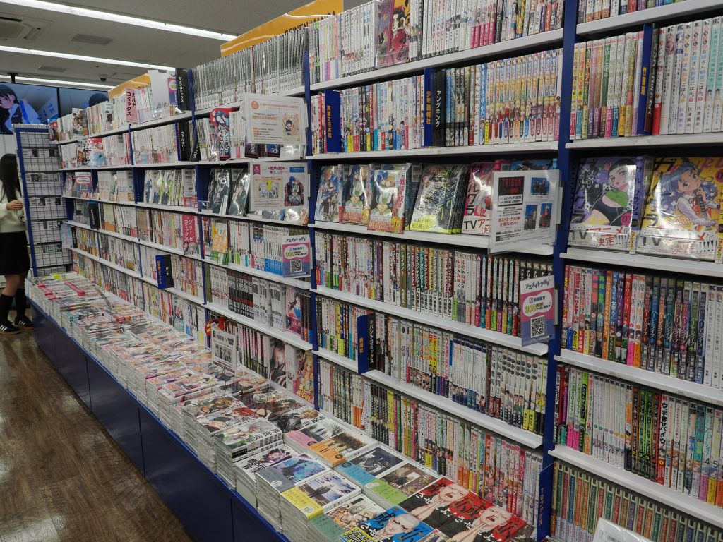 Ściana z mangą w Animate Ikebukuro - dziesiątki tytułów w rzędach, etykiety z tytułami i numerami tomów