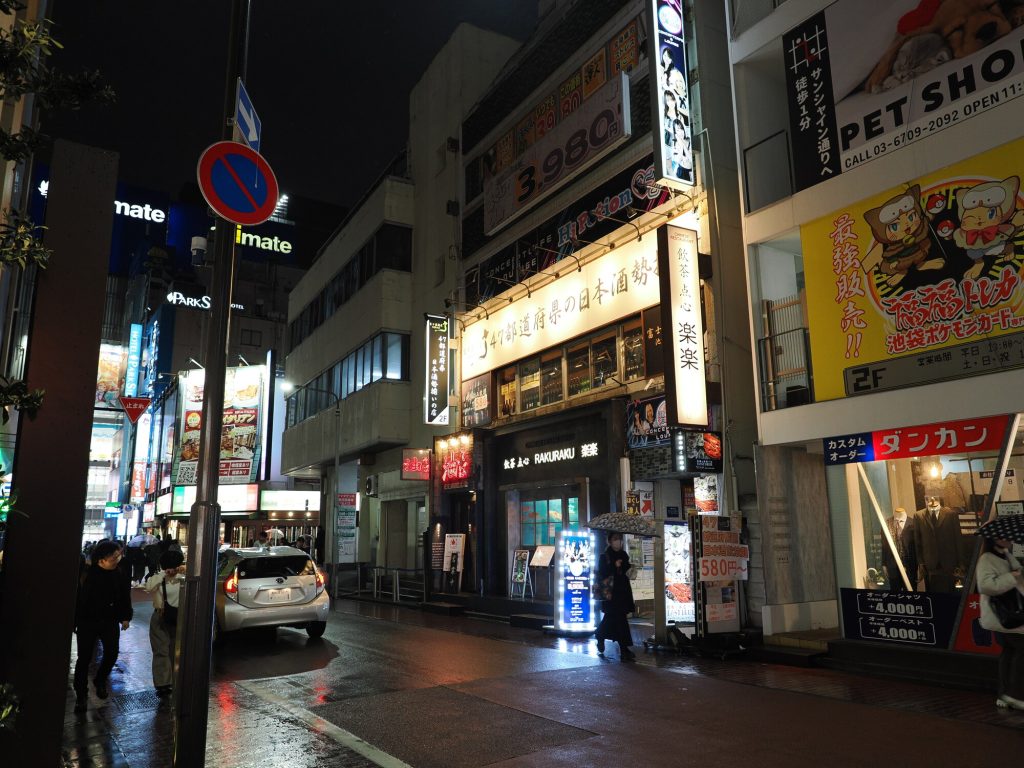 Nocna ulica Ikebukuro - Rakuraku izakaya z sake 47 prefektur, PET SHOP szyld po prawej, reklamy na budynkach