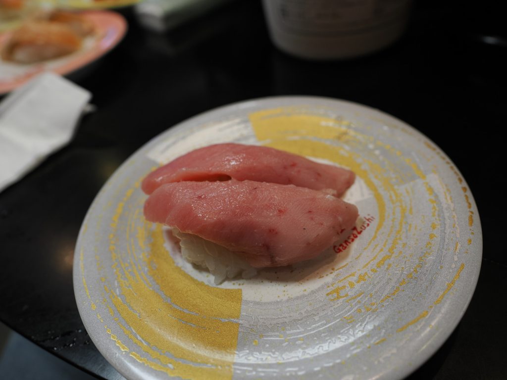 Dwa nigiri z toro tłustym tuńczykiem na białym talerzyku Ganso Zushi ze złotymi akcentami