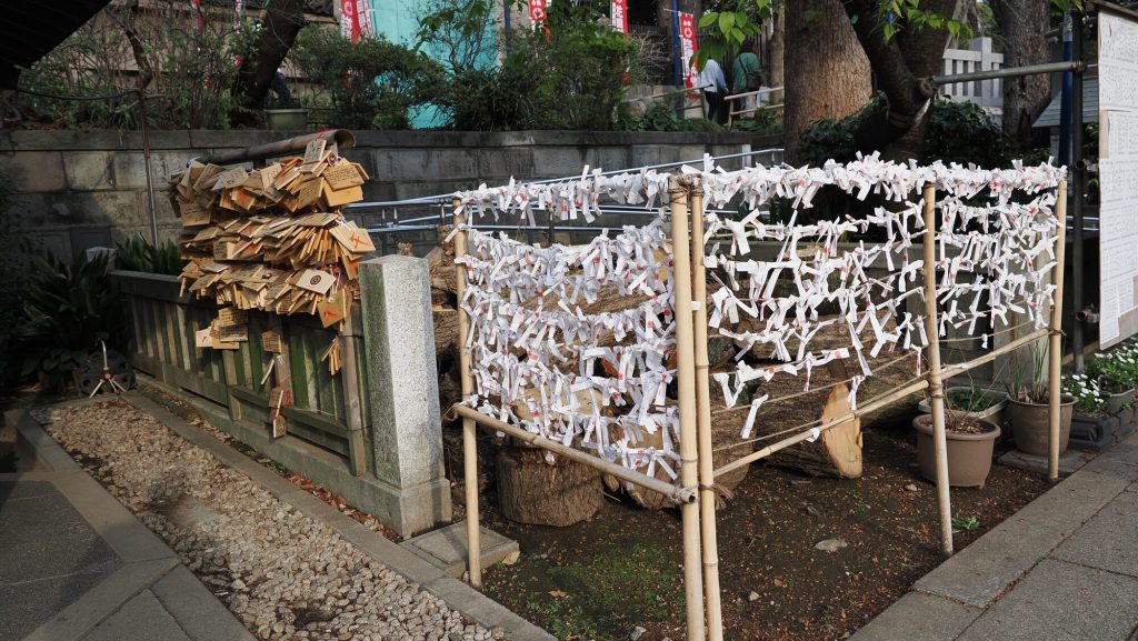 Tabliczki ema i zwoje omikuji przy świątyni Hanazono Inari Jinja w Ueno