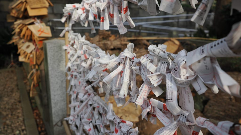 Zbliżenie na zawiązane omikuji na bambusowej ramie przy świątyni