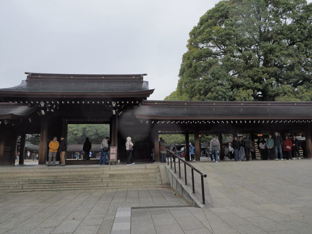 Glowna brama haiden sanktuarium Meiji Jingu, kolejka turystow, ciemne drewniane konstrukcje