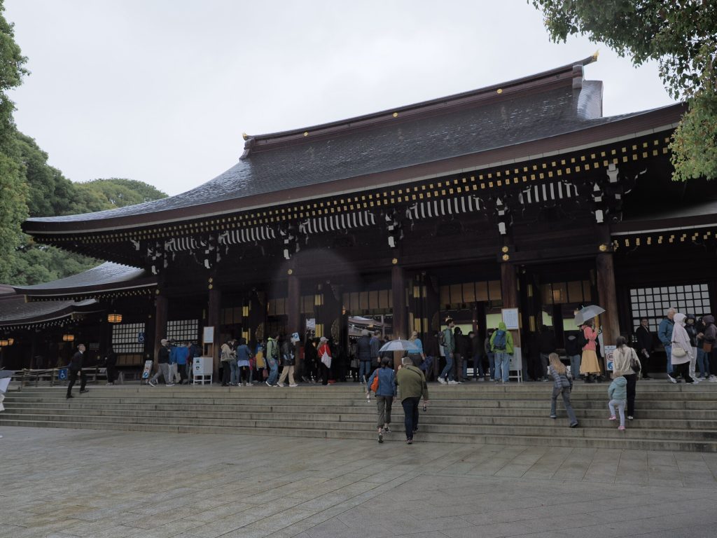 Haiden Meiji Jingu - szerokie ujecie hali modlitewnej z kolejka w deszczu