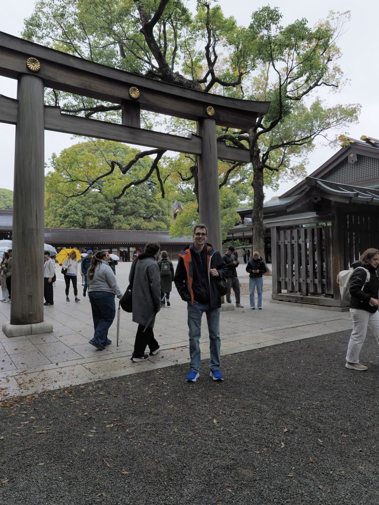 Kamil przed torii Meiji Jingu na dziedzinico sanktuarium, zlote chrysantemy na belce