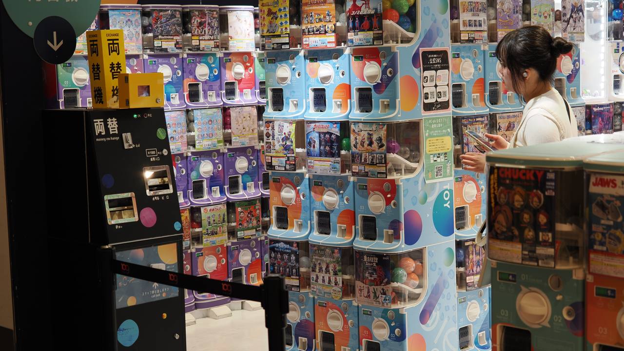 Kobieta przy automatach gacha w C-pla, sciany automatow, maszyny wymiany monet 両替