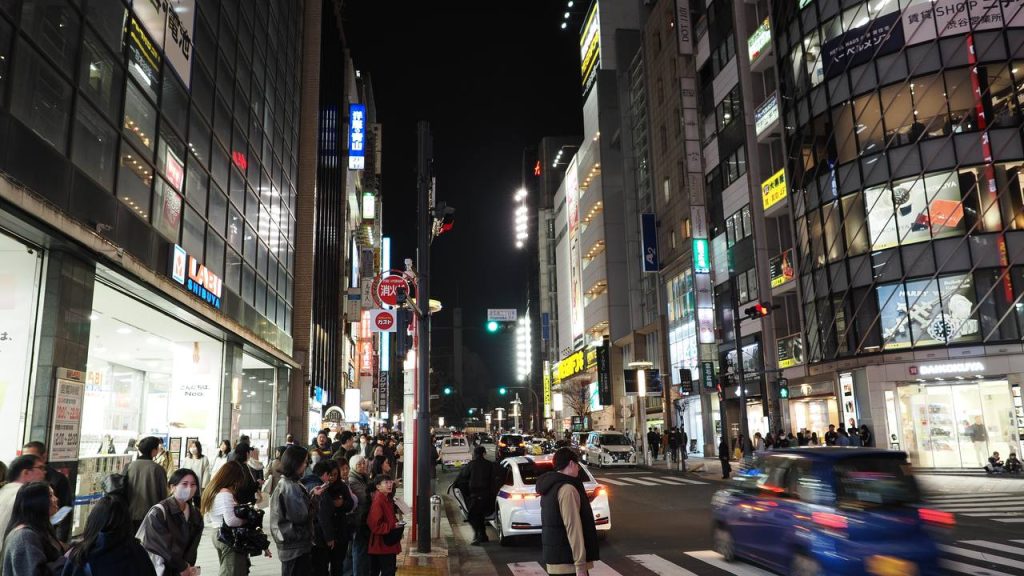 Nocna ulica Shibuya z LABI Shibuya po lewej i Yamaha po prawej, skrzyzowanie z sygnalizacja, ruch uliczny