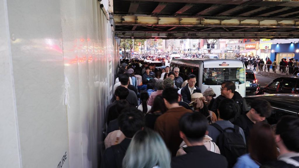 Ścisk pod wiaduktem przy Shibuya - tłum pieszych przepychający się wąskim przejściem obok samochodów