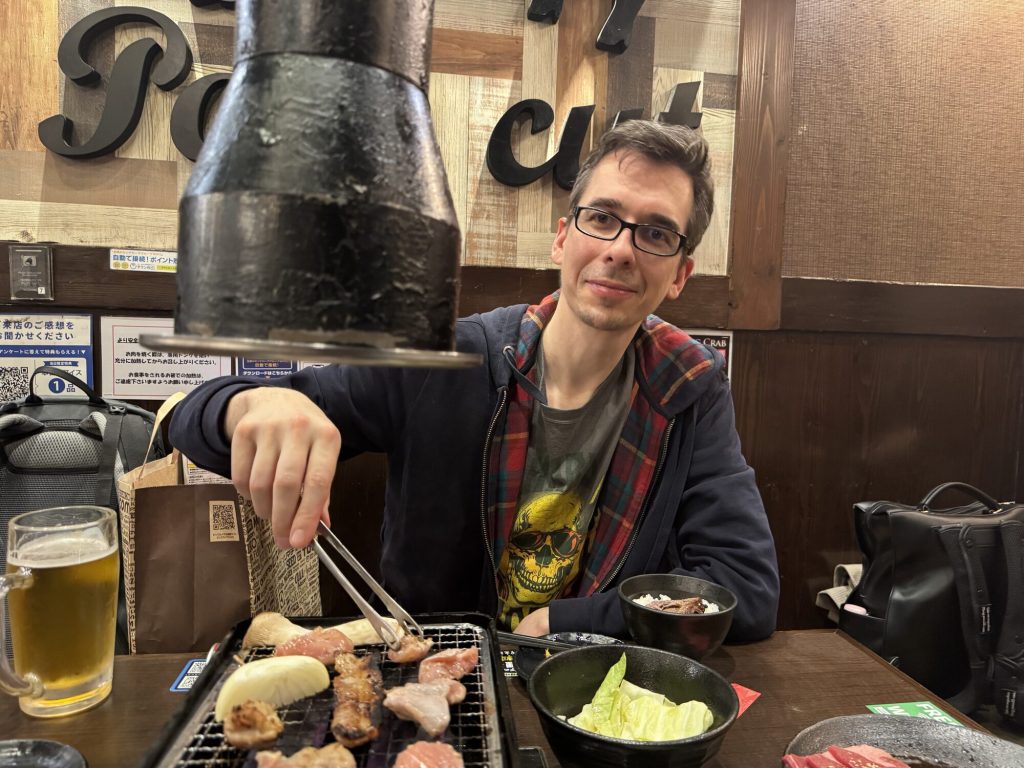 Człowiek u szczytu możliwości. Szczypce w dłoni, mięso na ogniu, uśmiech mówi wszystko. 🔥