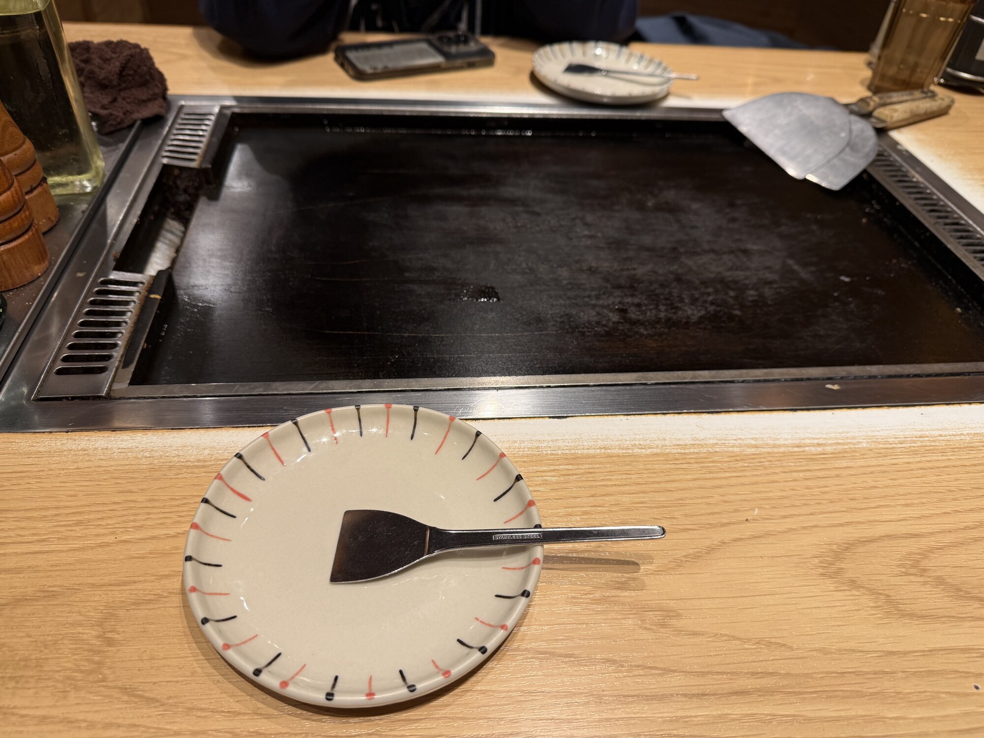 Teppan przy stoliku w restauracji teppanyaki — płyta, talerzyk i łopatka