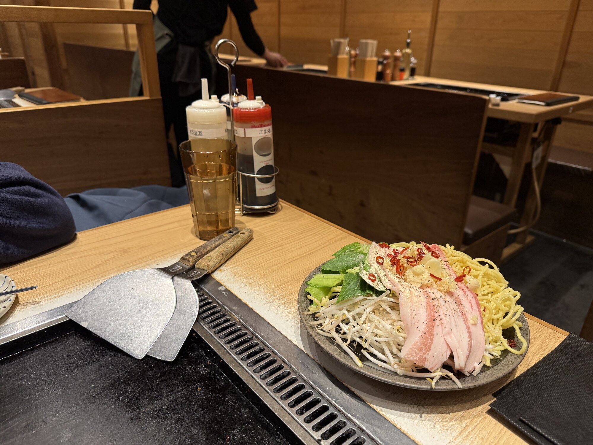 Stolik w restauracji teppanyaki — surowe składniki na kamieniu, sosy, szpatułki, piwo