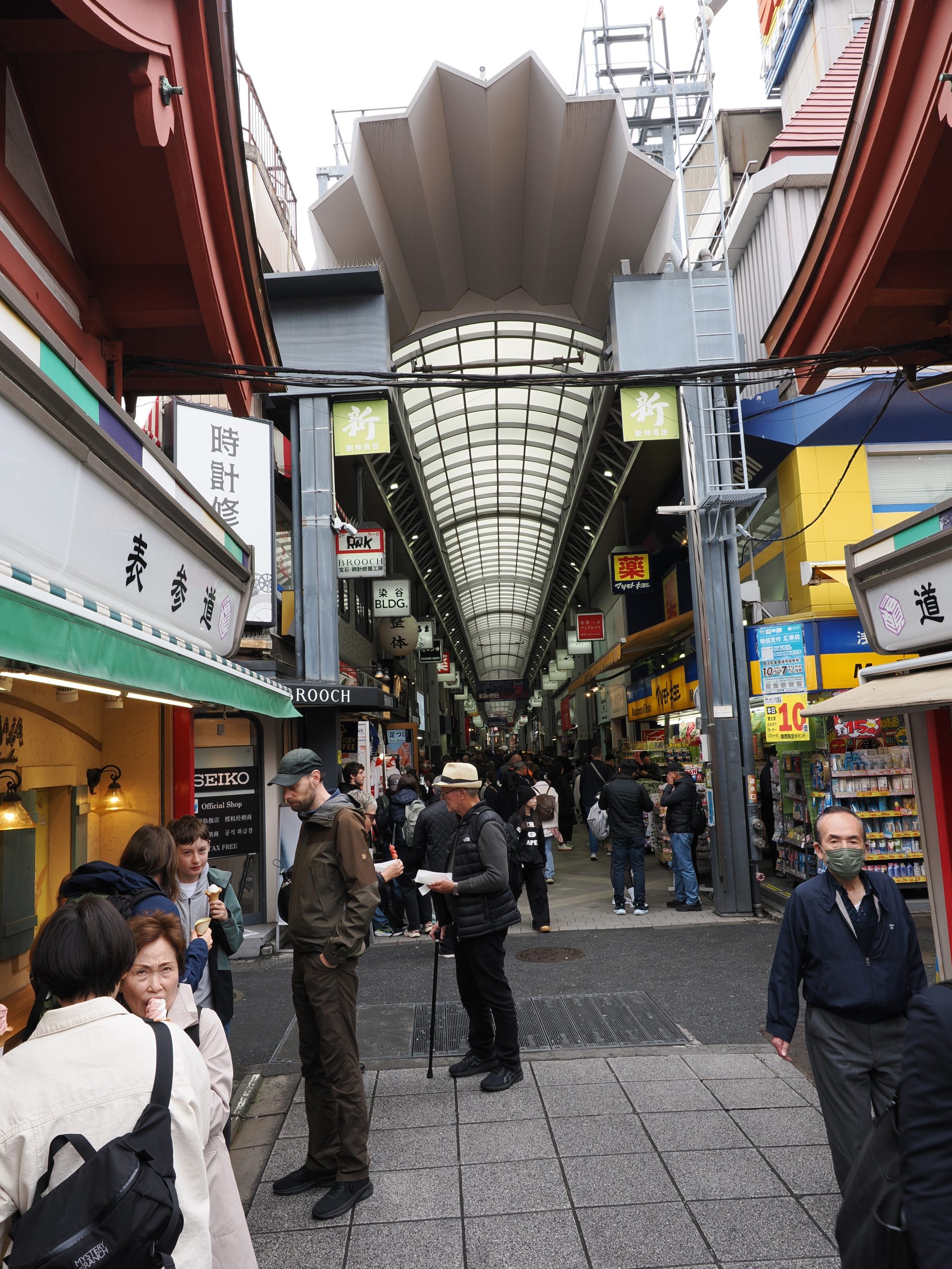 Zadaszone przejście handlowe ze szklanym dachem, sklep Seiko, naprawa zegarków, tłum turystów