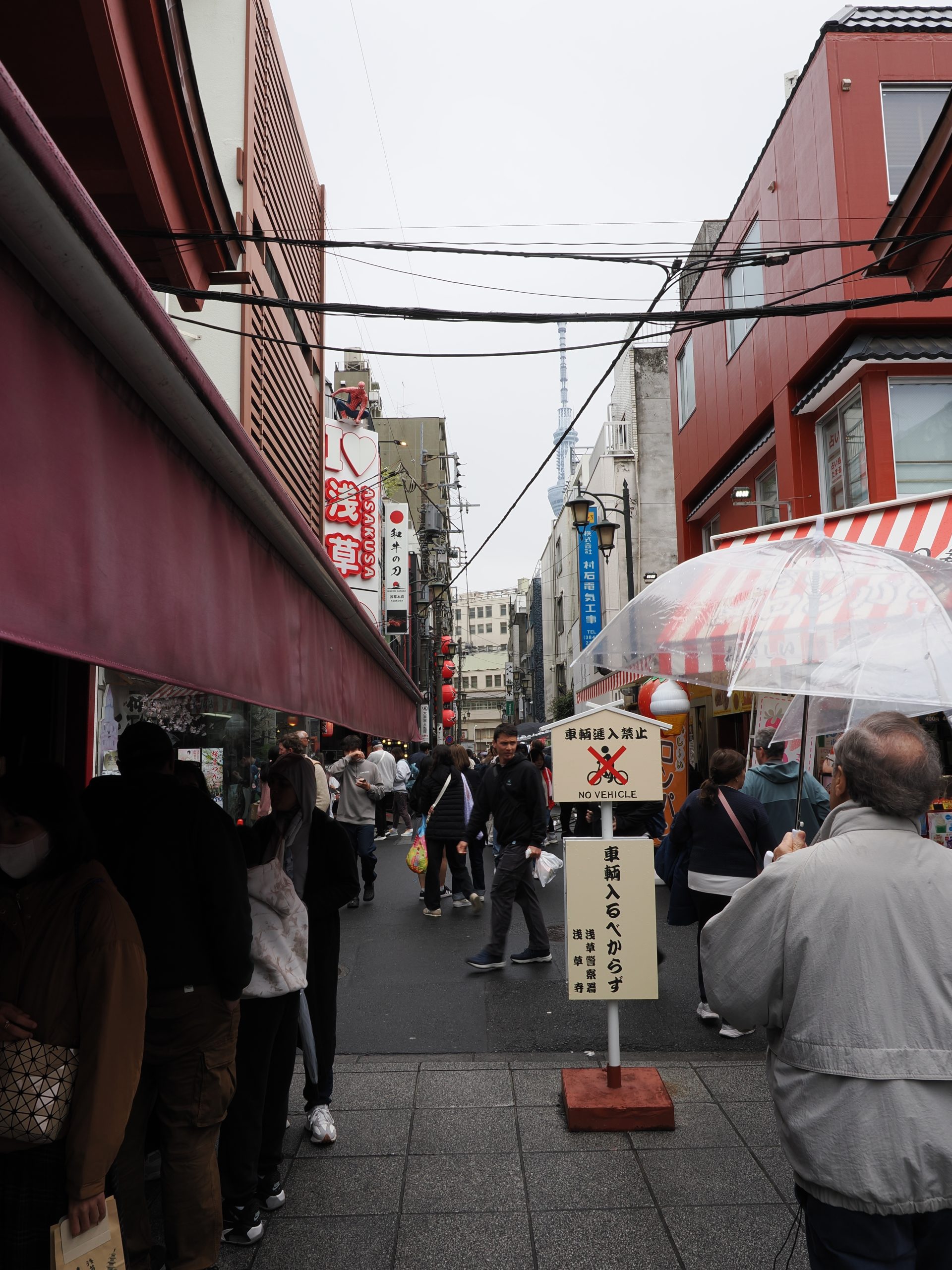 Boczna uliczka w Asakusie z szyldem I love Asakusa, Tokyo Skytree widoczne między budynkami w tle