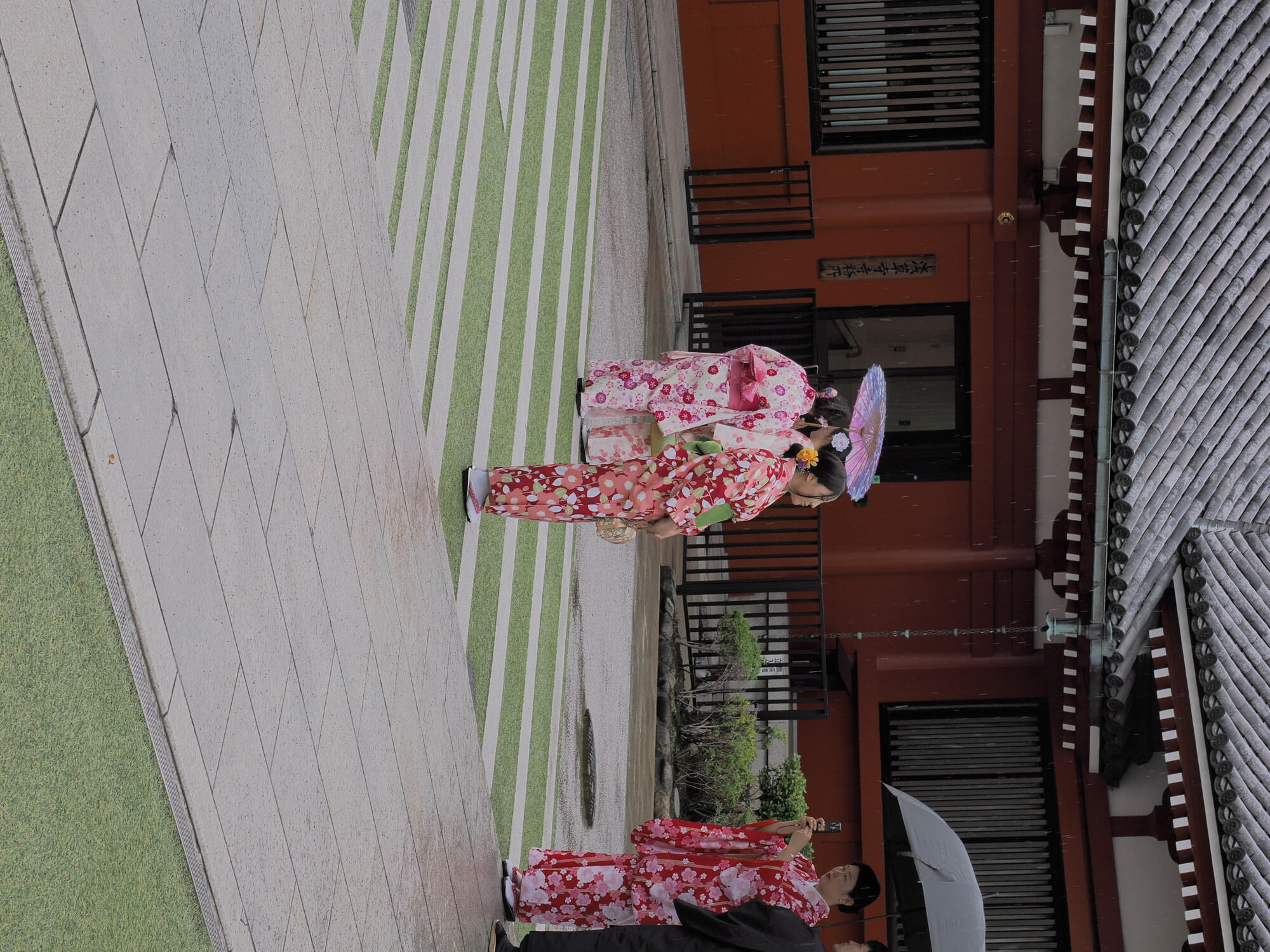 Kobiety w kolorowych kimono z parasolkami na dziedzińcu Senso-ji w deszczu