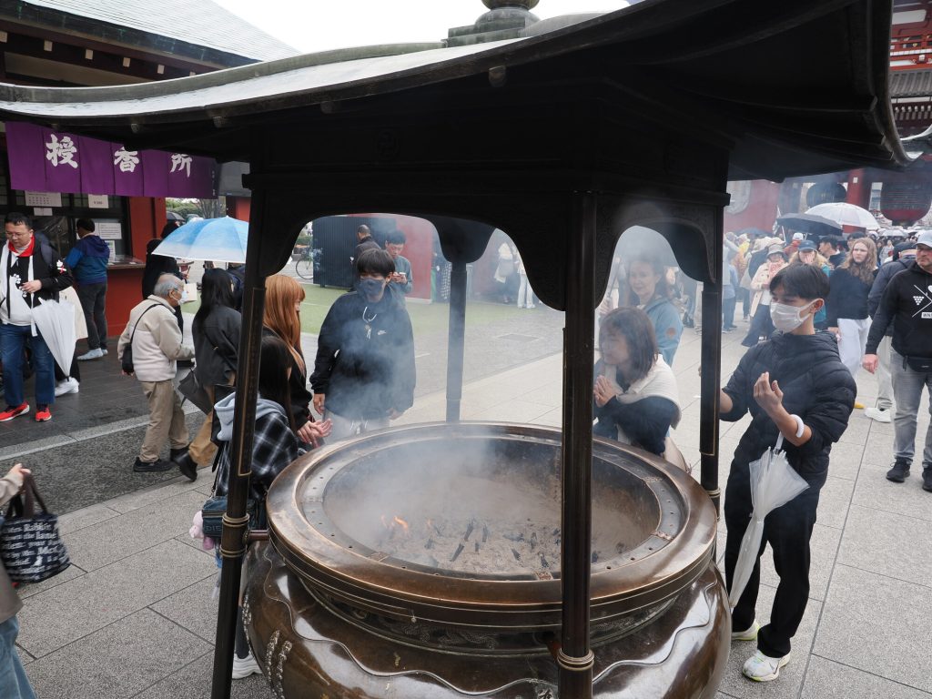 Kocioł kadzidlany przy Senso-ji z szerszej perspektywy, purpurowy baner w tle