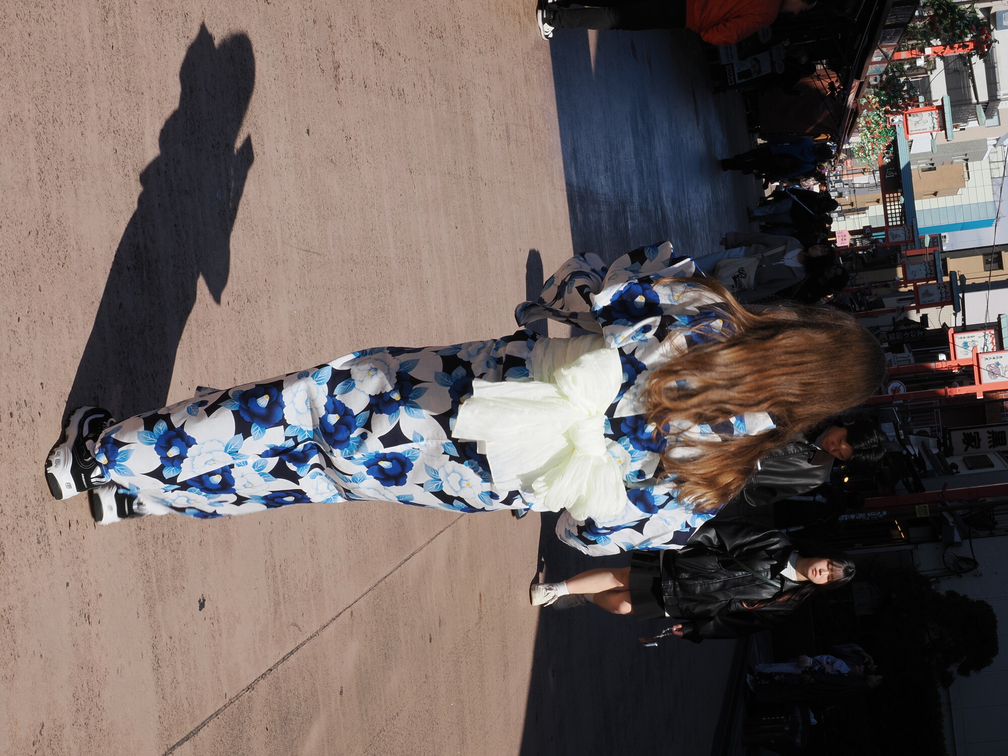 Dziewczyna w niebieskiej yukacie z kremowym obi spaceruje po Nakamise-dori