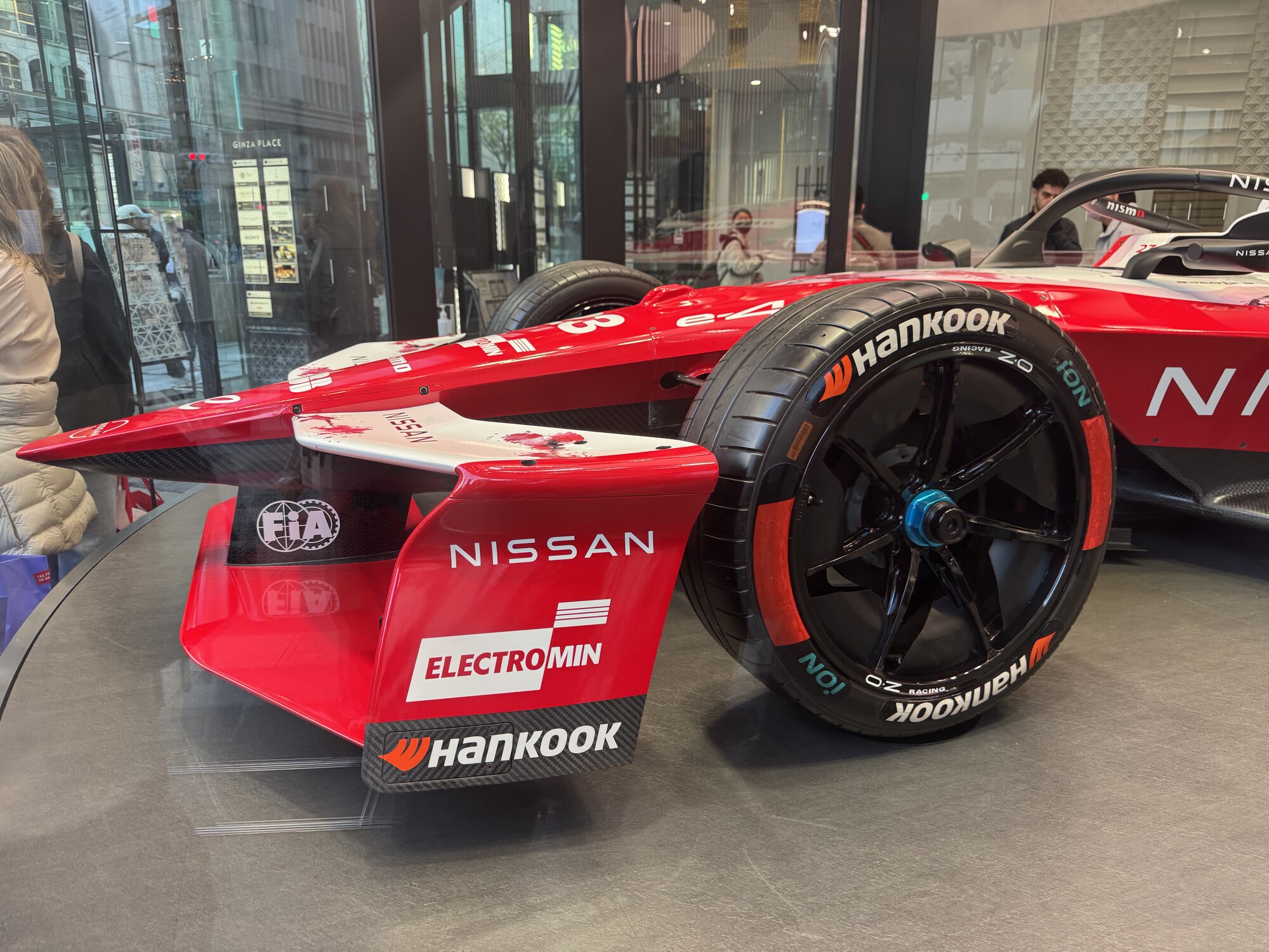 Przednie skrzydło bolidu Nissana z bliska, logo FIA i opony OZ Racing