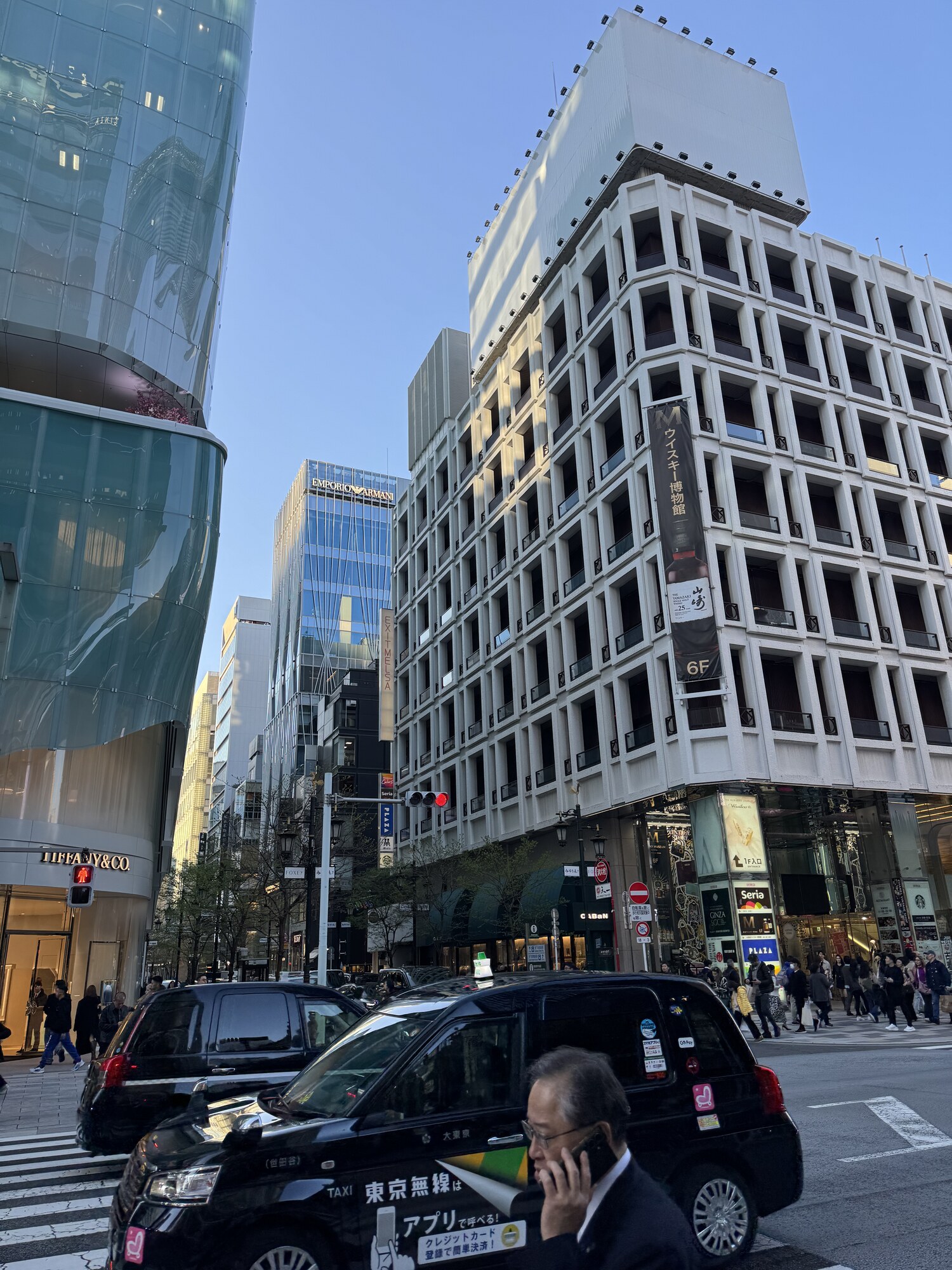 Ulica w Ginzie z taksówką Tokyo Musen, mężczyzna w garniturze, w tle Emporio Armani i Muzeum Whisky