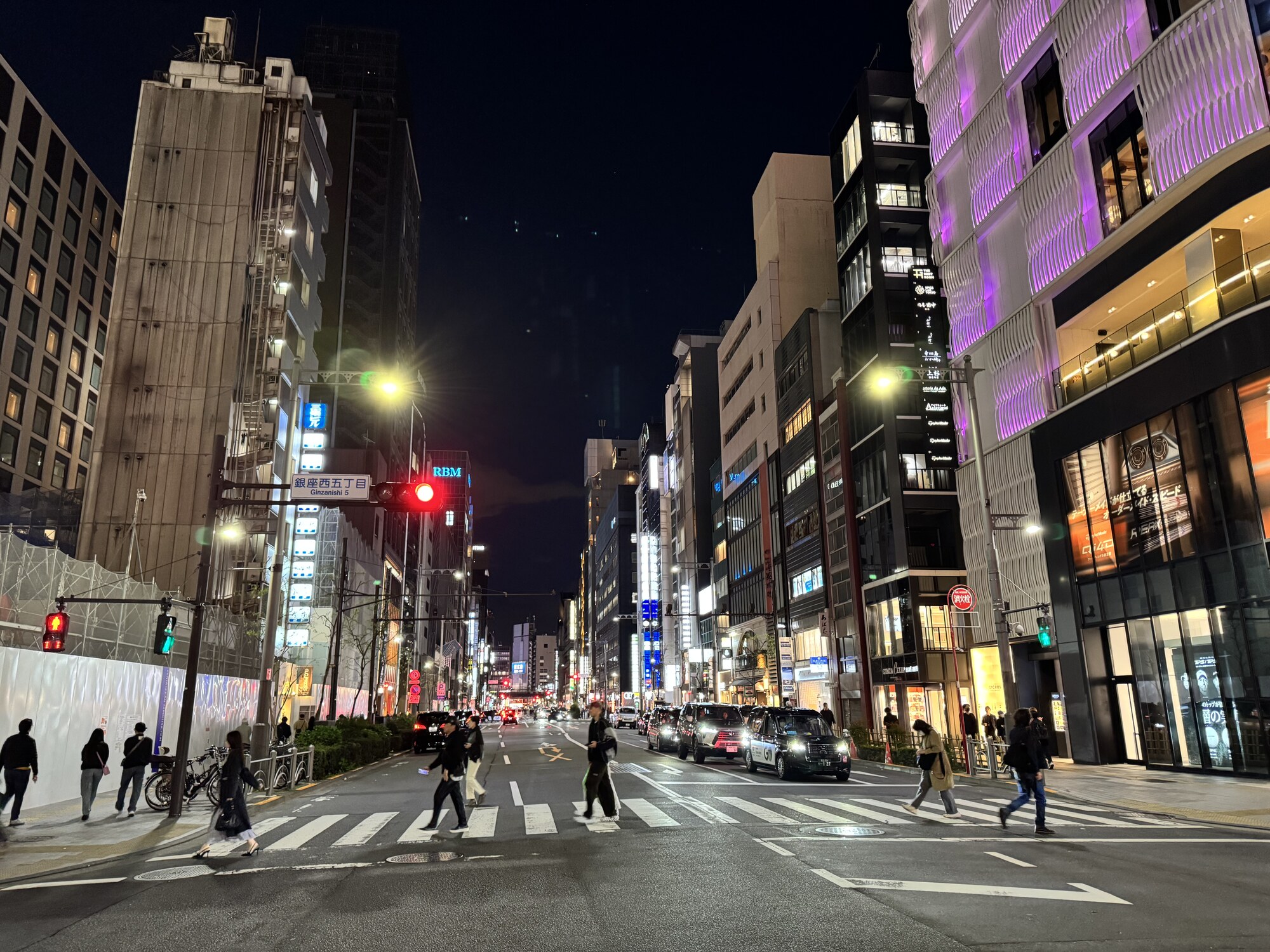 Nocne skrzyżowanie Ginzanishi 5-chome z fioletowymi iluminacjami i tłumem przechodniów