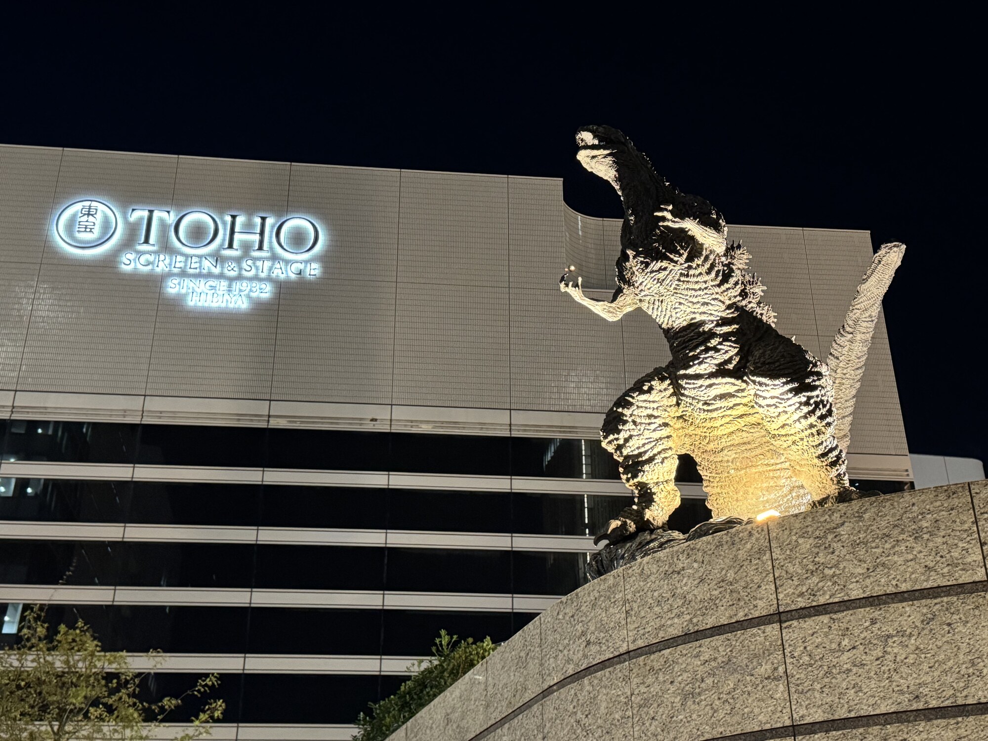 Podświetlona rzeźba Godzilli przed kinem TOHO Hibiya nocą