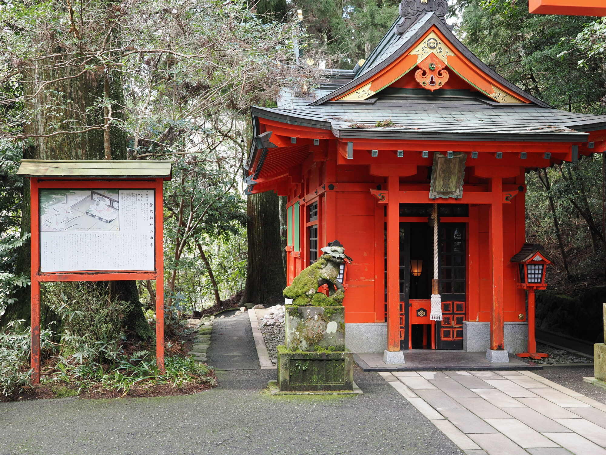 Boczna kaplica Hakone Jinja z tablicą informacyjną i komainu pokrytym mchem