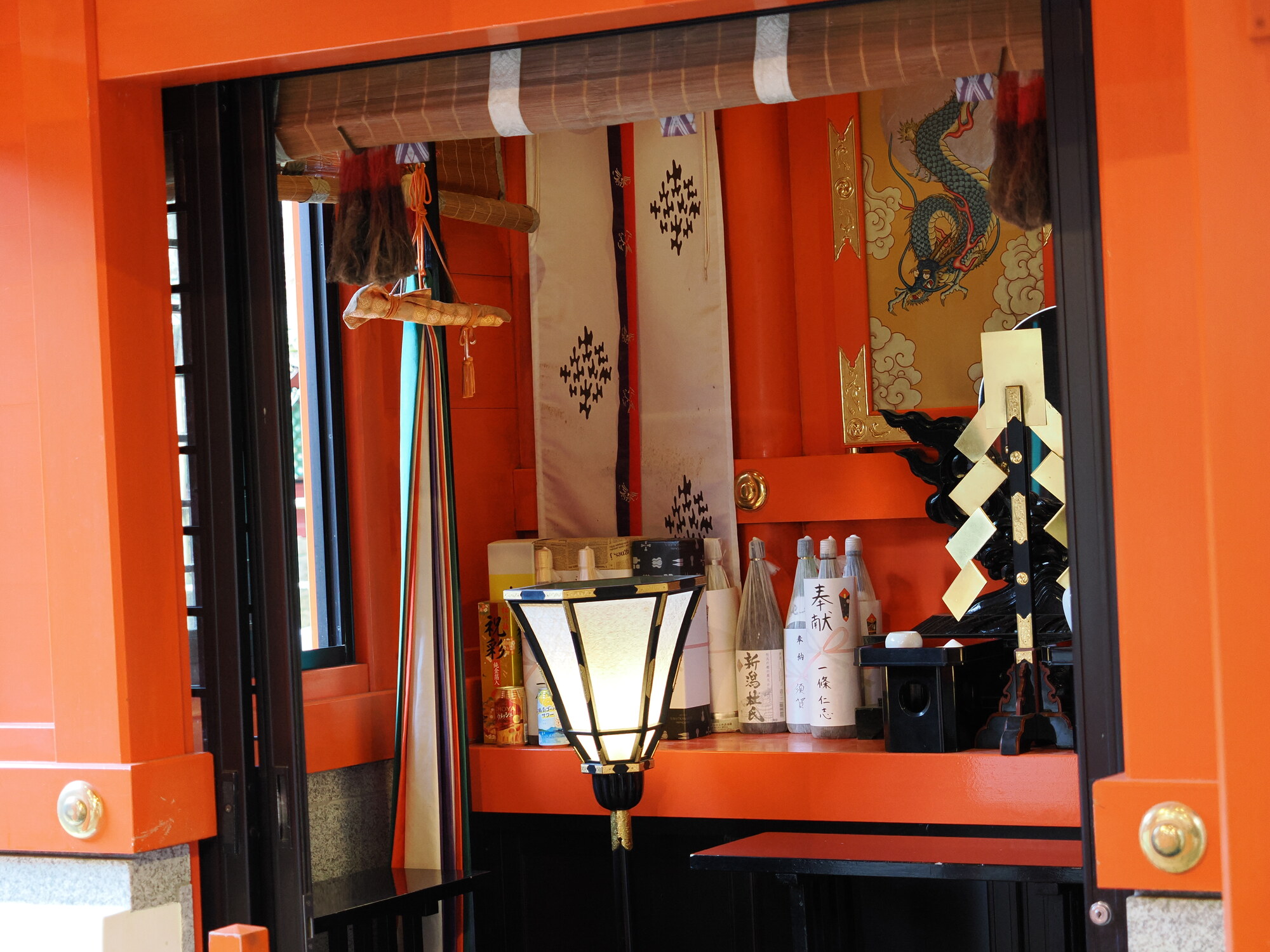 Wnętrze kaplicy Kuzuryu Jinja — butelki sake, złoty smok i lampion