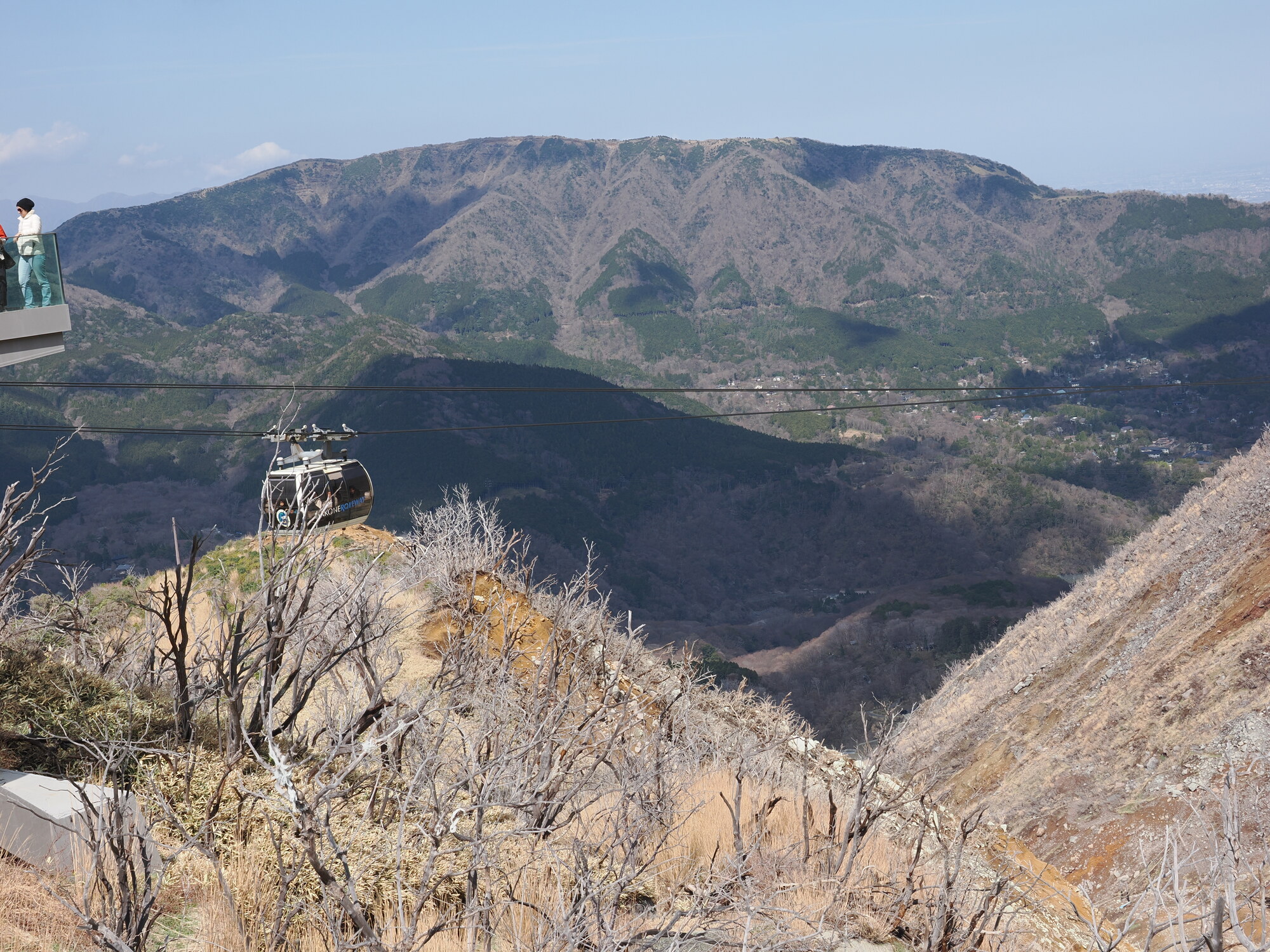 Gondola kolejki linowej na tle wulkanicznego krajobrazu Owakudani — żółte skały siarkowe i panorama gór