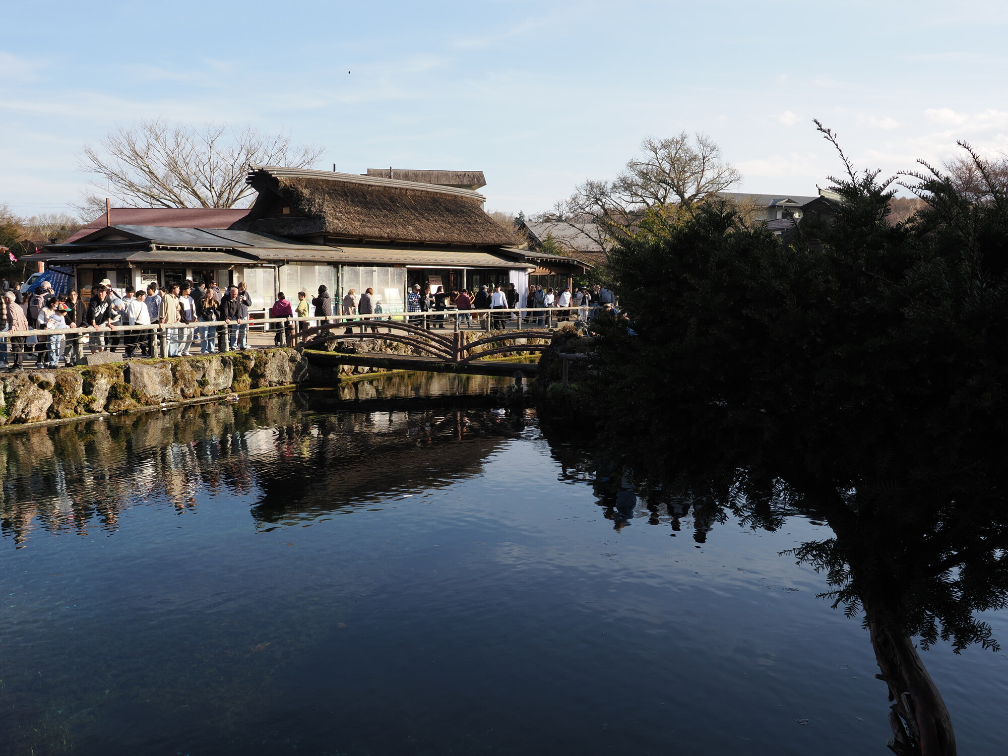 Panorama stawów Oshino Hakkai z odbiciem nieba w wodzie, tłum turystów