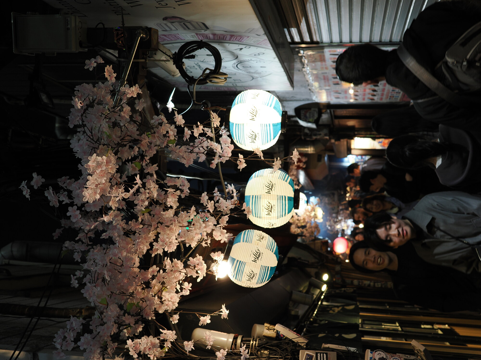 Zbliżenie lampionów i sztucznej sakury w Omoide Yokocho — lampiony hiLike i tłum