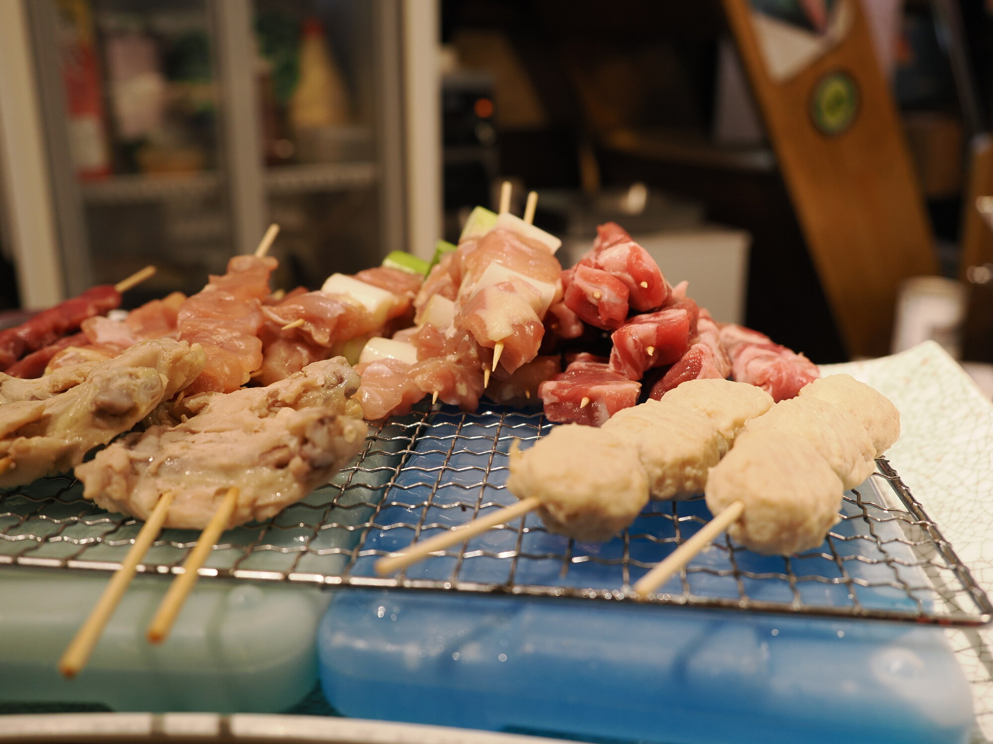 Surowe szaszłyki yakitori na ruszcie — kurczak, boczek z cebulą, wołowina i klopsiki tsukune