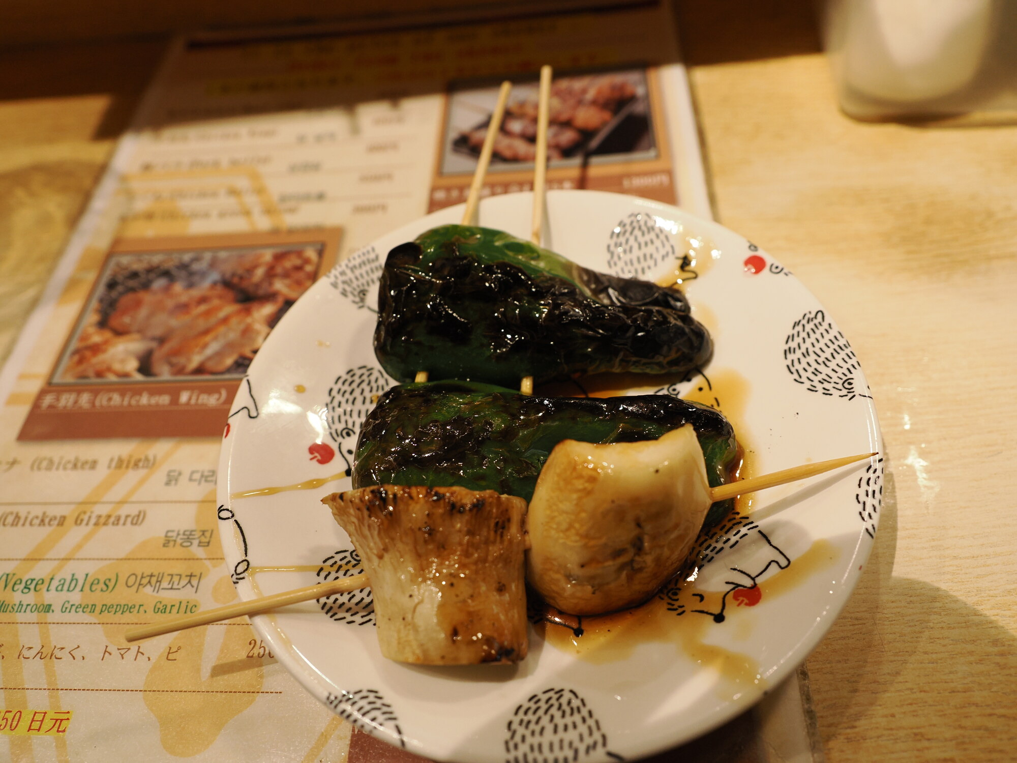 Zgrillowane warzywa na talerzu — papryczki shishito i cebula polane sosem tare