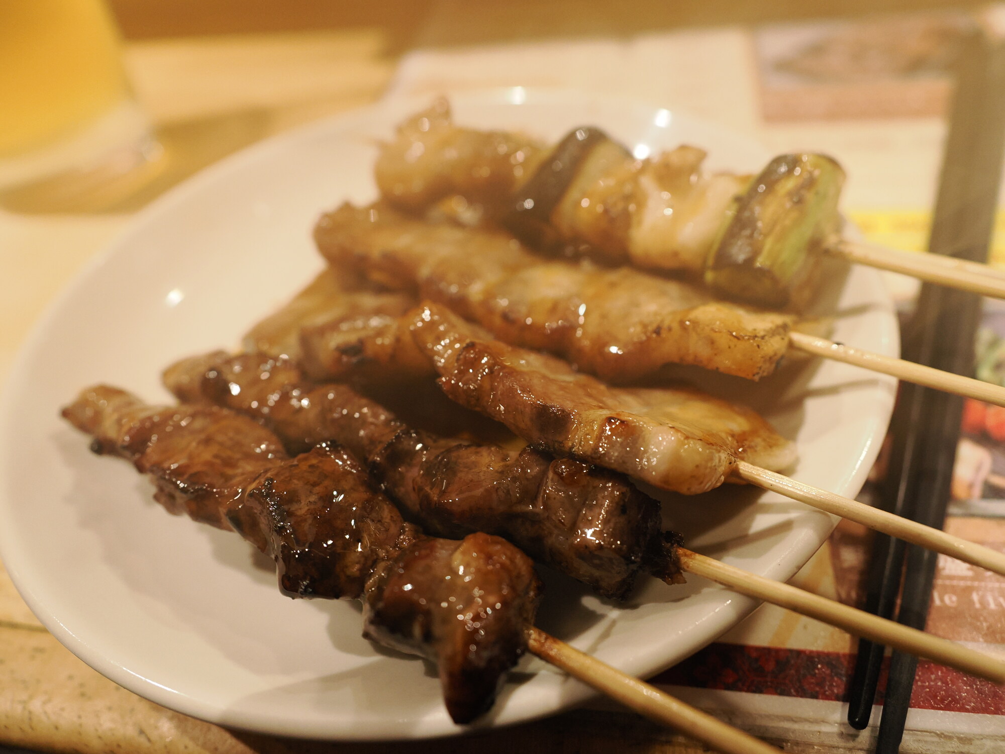 Gotowe szaszłyki yakitori na talerzu — wołowina i kurczak z cebulką polane sosem tare