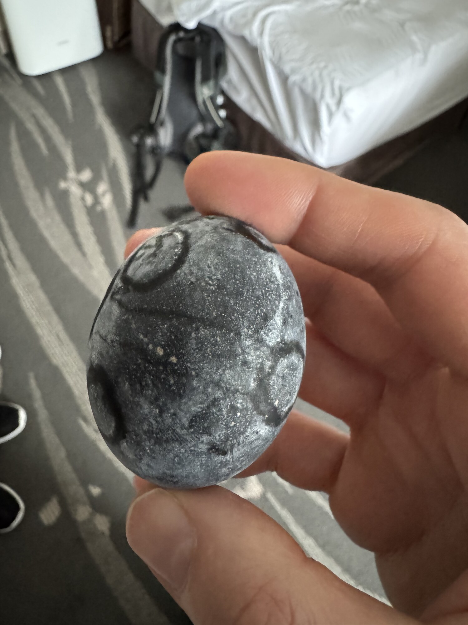 Czarne jajko z Owakudani w dłoni na tle wulkanicznego krajobrazu i dymu fumarolicznego