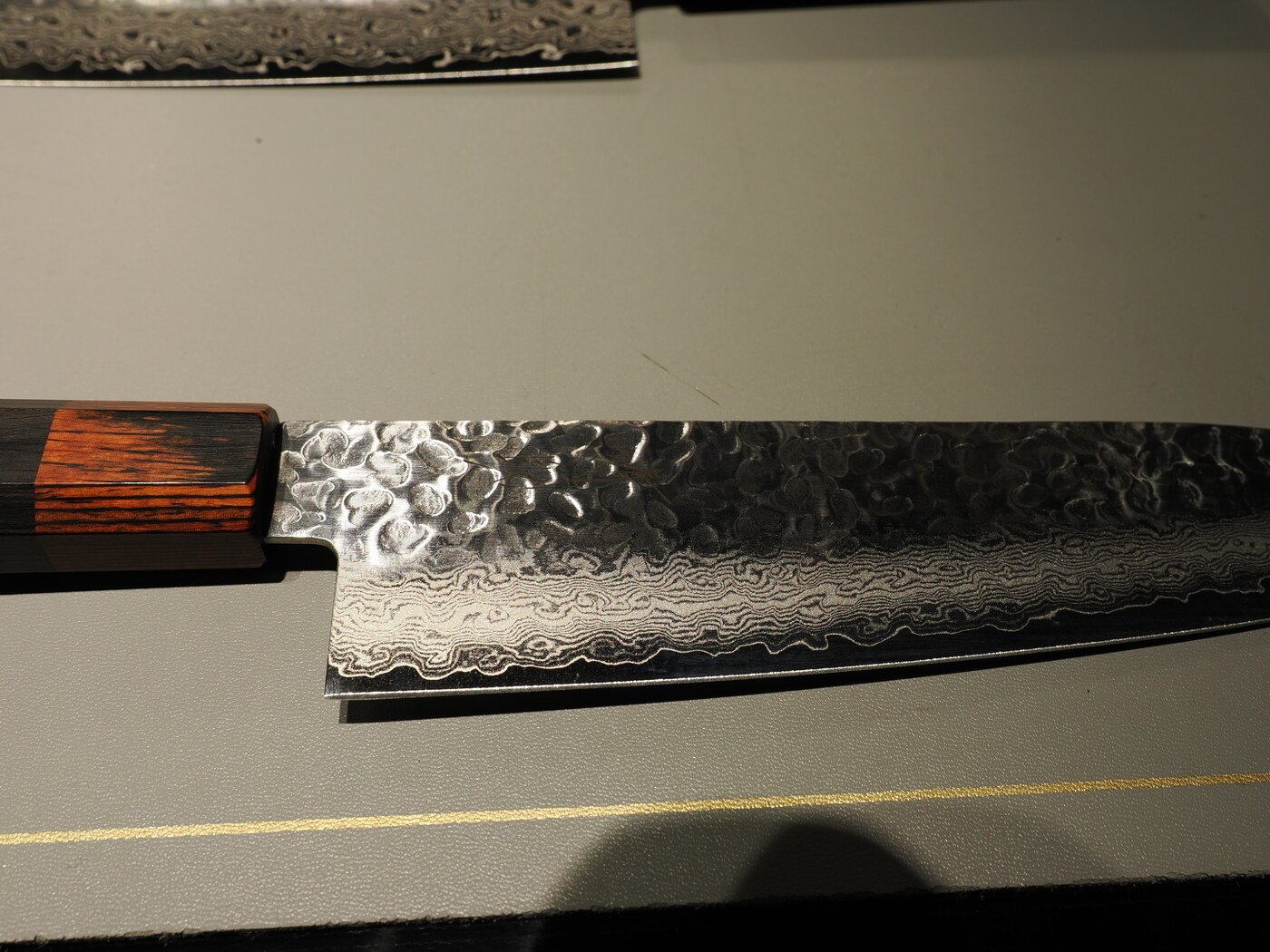 Zbliżenie ostrza noża damasceńskiego — wzór fal na stali, trzonek z drewna różanego