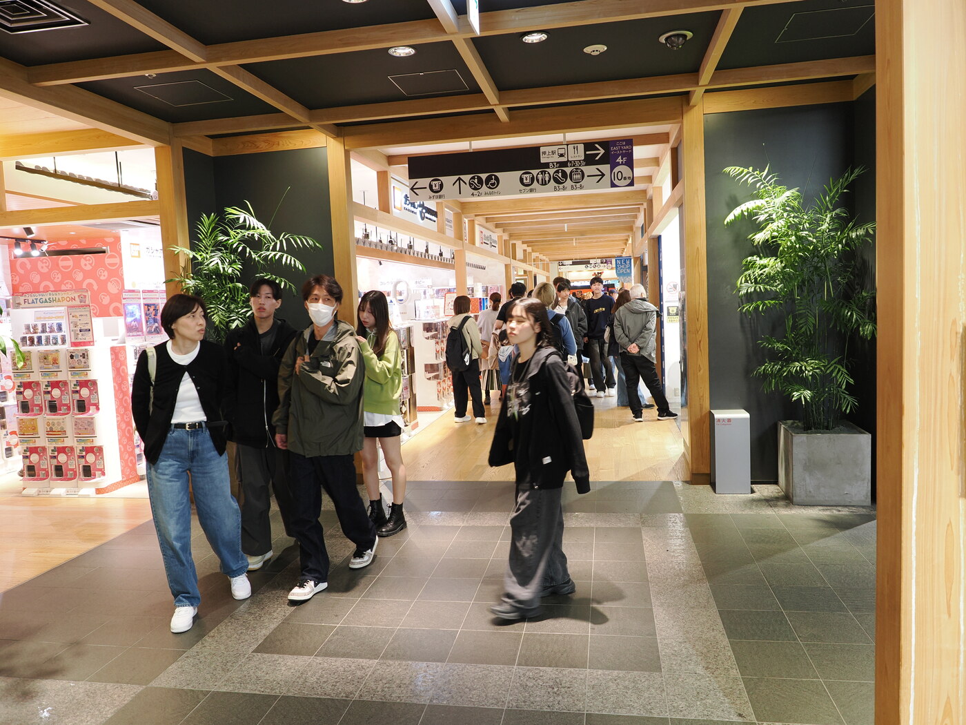 Korytarz handlowy Solamachi — drewniane wykończenia, sklep FLAT GASHAPON po lewej, drogowskazy w głębi