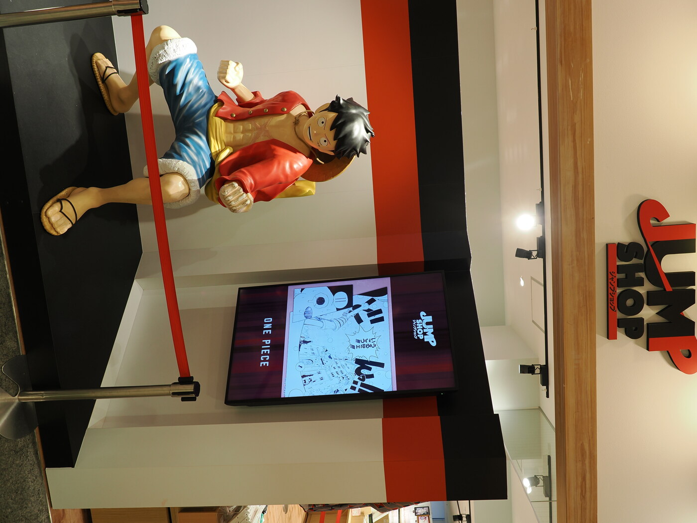 Jump Shop w Solamachi — figurka Monkey D. Luffy w naturalnej wielkości przy wejściu, ekran z One Piece w tle