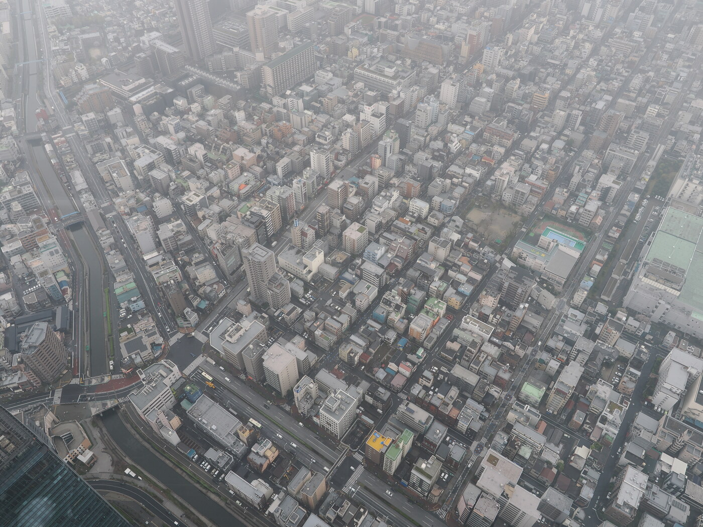 Widok z Tokyo Skytree Tembo Deck 350m — rzędy bloków Tokio we mgle, kanały i zabudowa dzielnicy Sumida z lotu ptaka