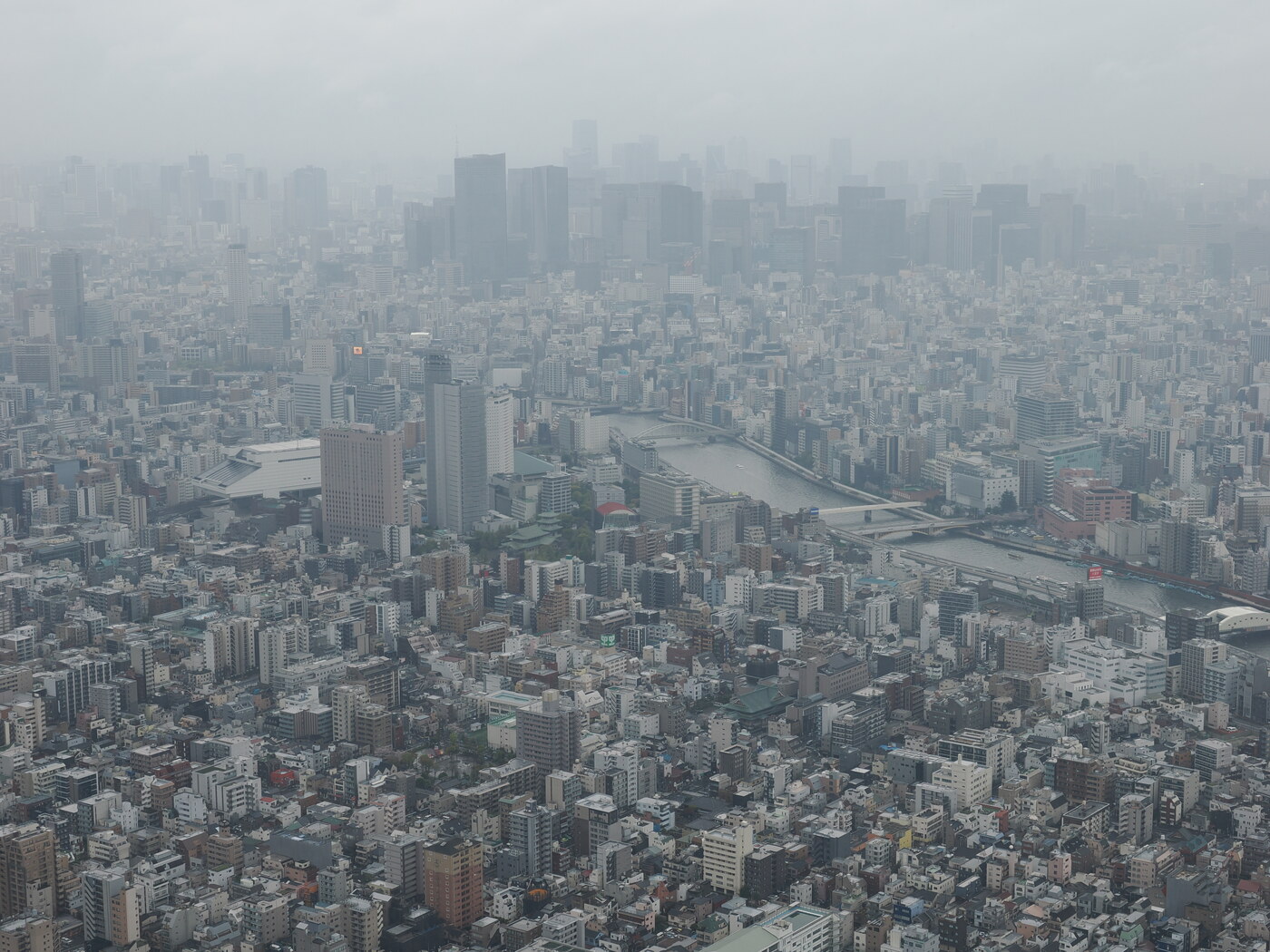 Panorama Tokio z Tembo Deck — mgliście, sylwetki wieżowców Shinjuku w tle, rzeka Sumida w centrum kadru