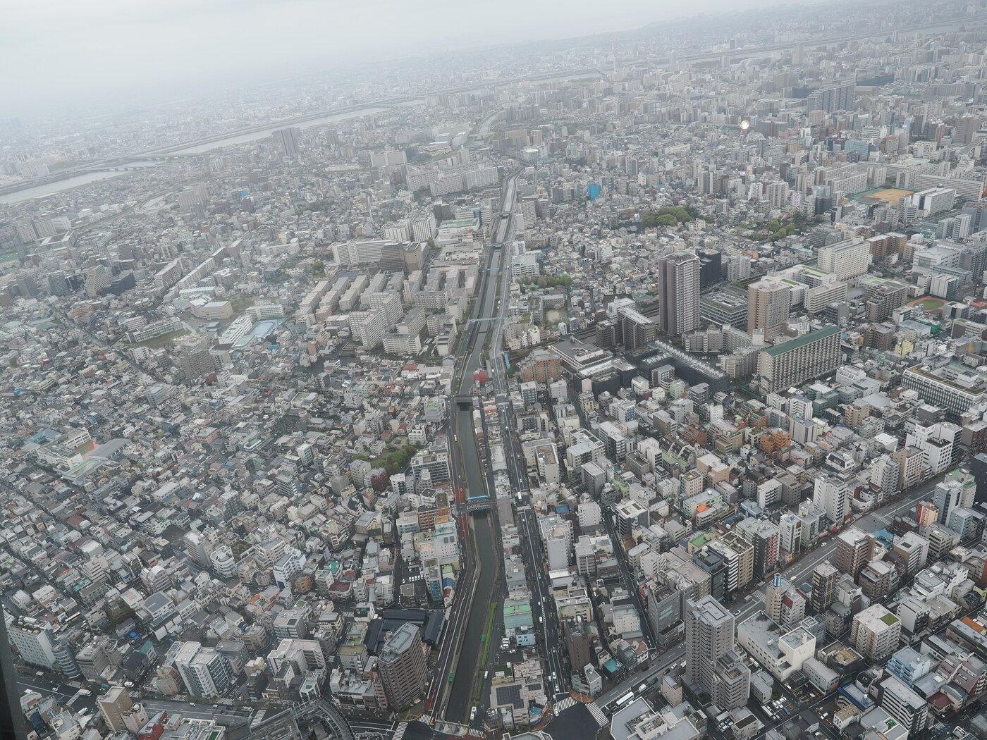 Widok z Tembo Deck na północ — kanał Kitajukken biegnący przez zabudowę, rzeka Arakawa i wały przeciwpowodziowe w tle