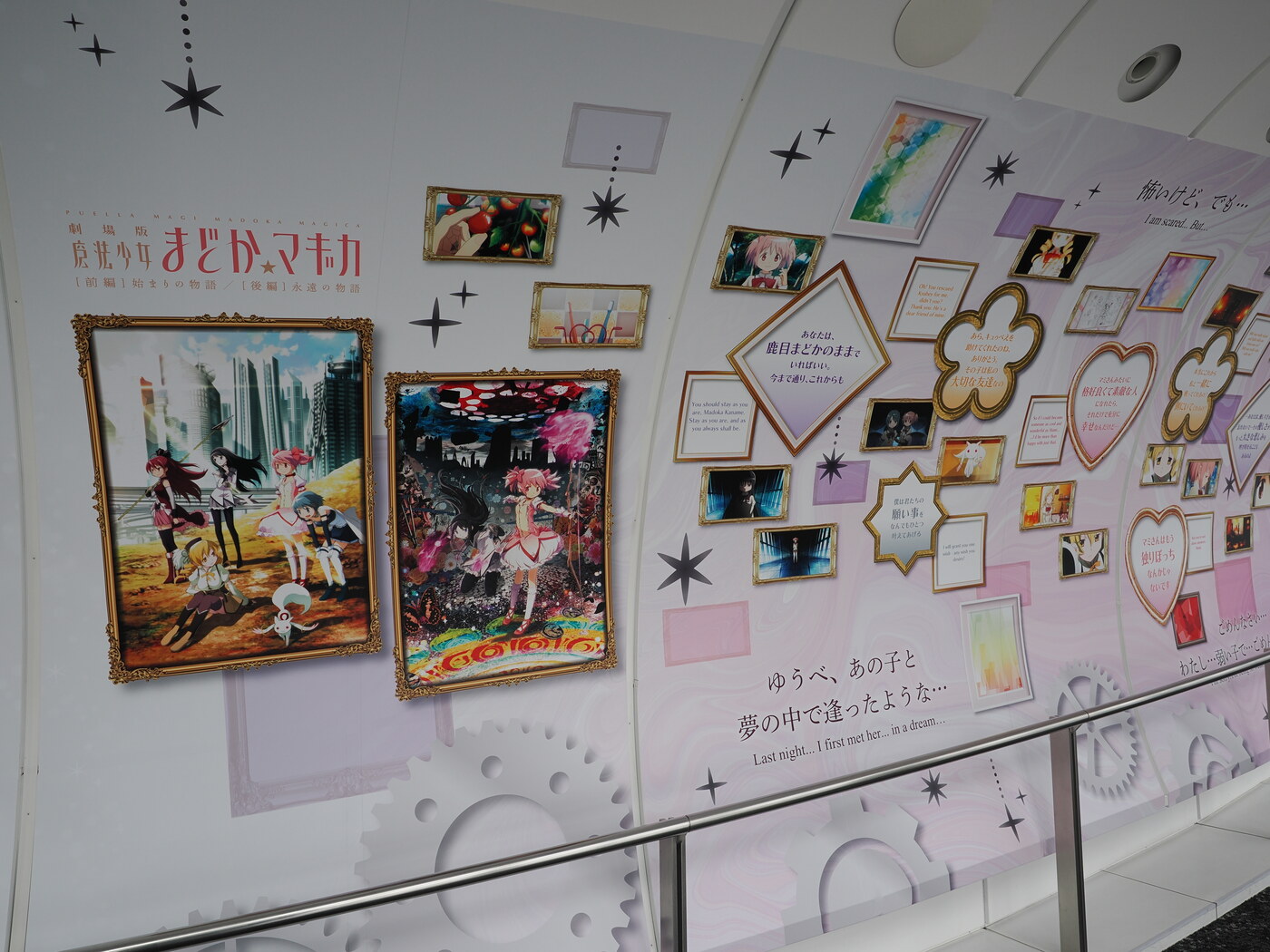 Ekspozycja Madoka Magica na Tembo Deck — ściana z grafikami i cytatami z serialu, po lewej plakaty filmowe w złotych ramach