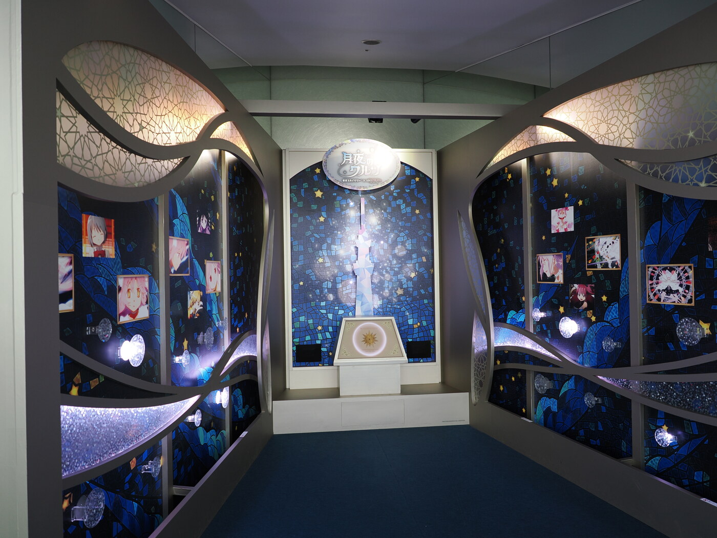 Instalacja 月夜のワルツ — Madoka Magica × Skytree — korytarz z mozaiką Skytree pośrodku, fotografie postaci i kryształy po bokach, oświetlenie niebieskie