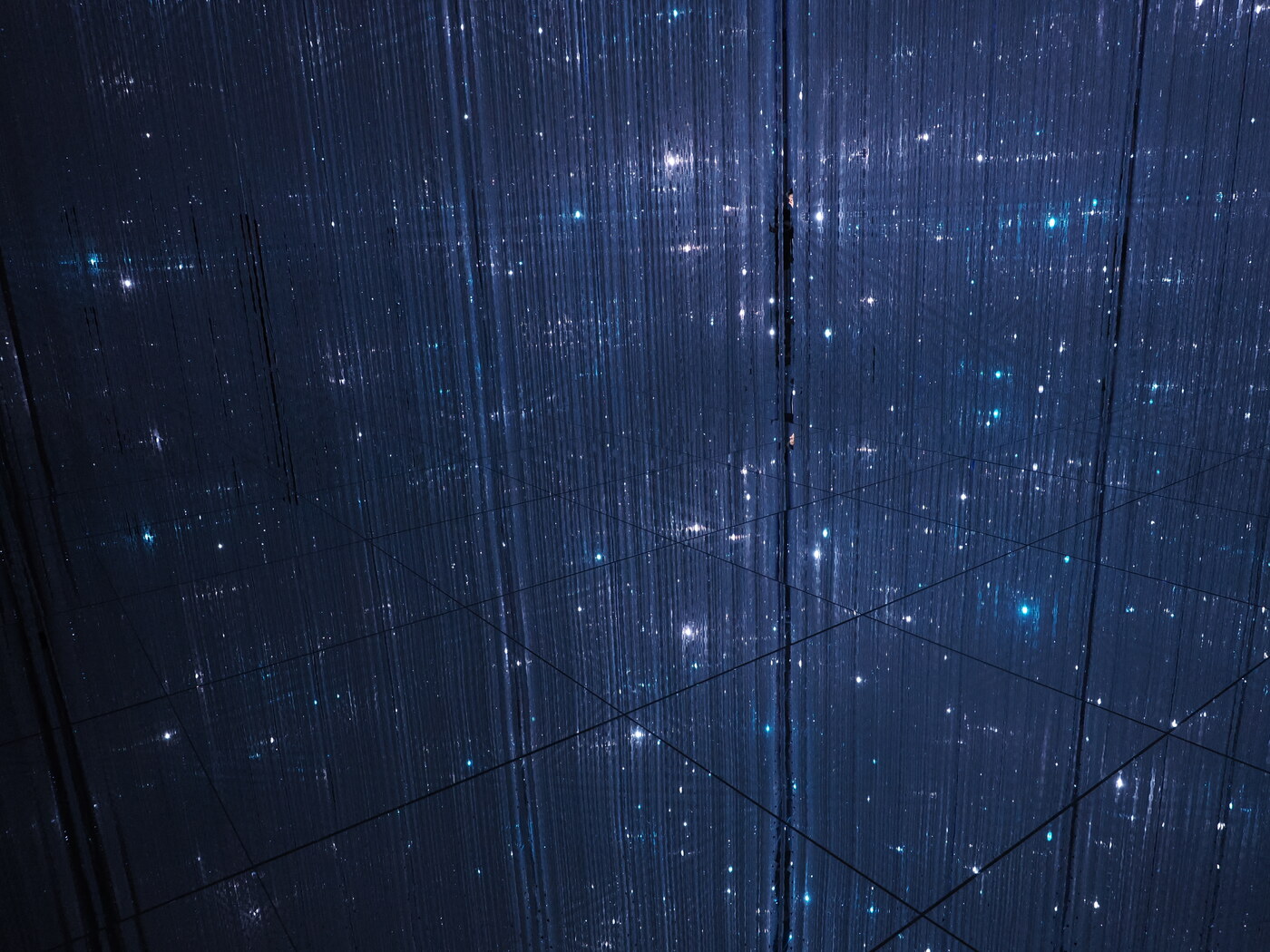 teamLab Planets — zbliżenie na niebieski sufit ze światłowodów — gwiezdna siatka z migoczącymi punktami, ramy paneli widoczne jako linie w mroku