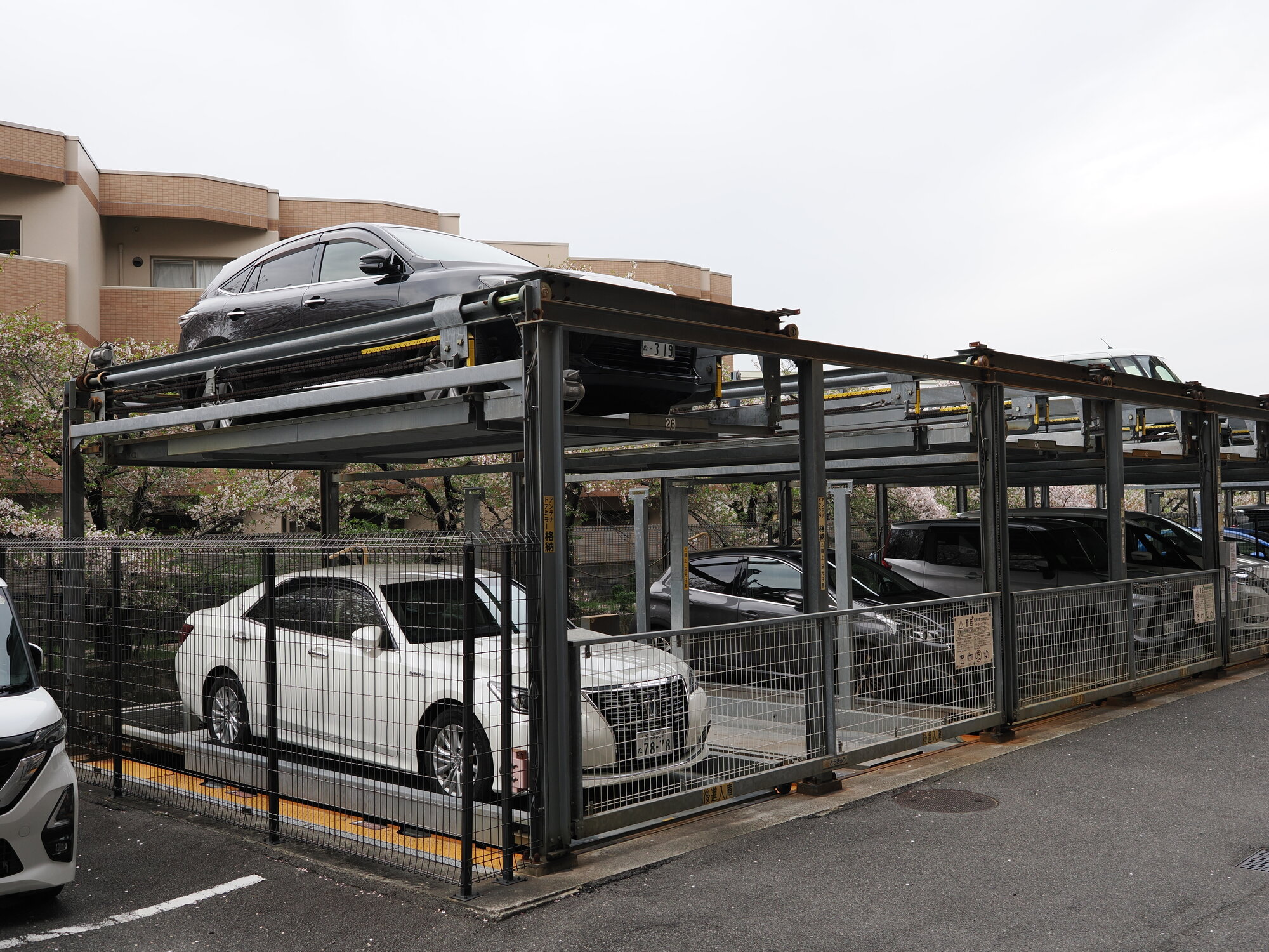 Mechaniczny parking piętrowy w Uji na tle sakury