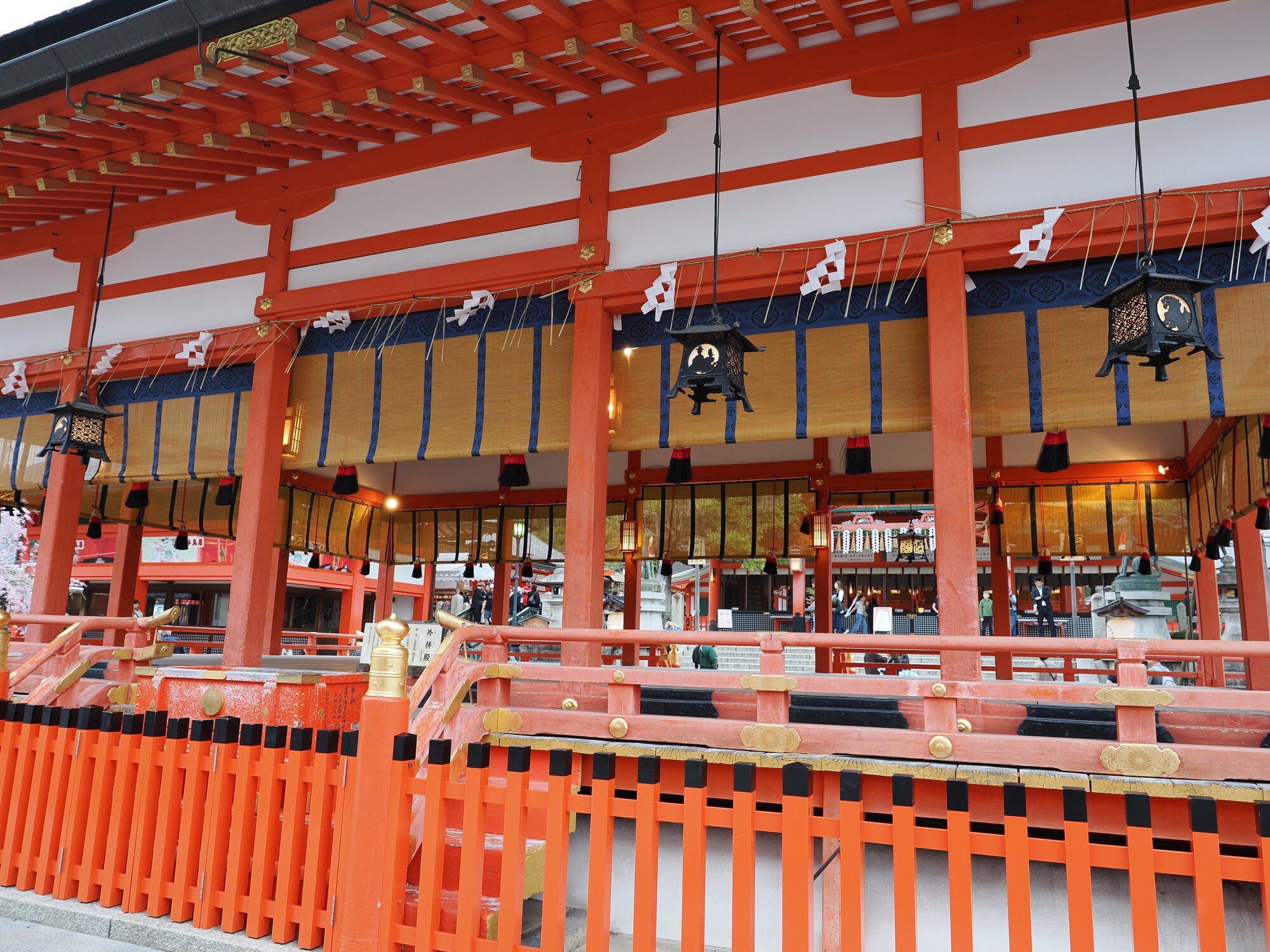 Wnętrze hali modlitewnej Fushimi Inari z lampionami i ozdobami shide