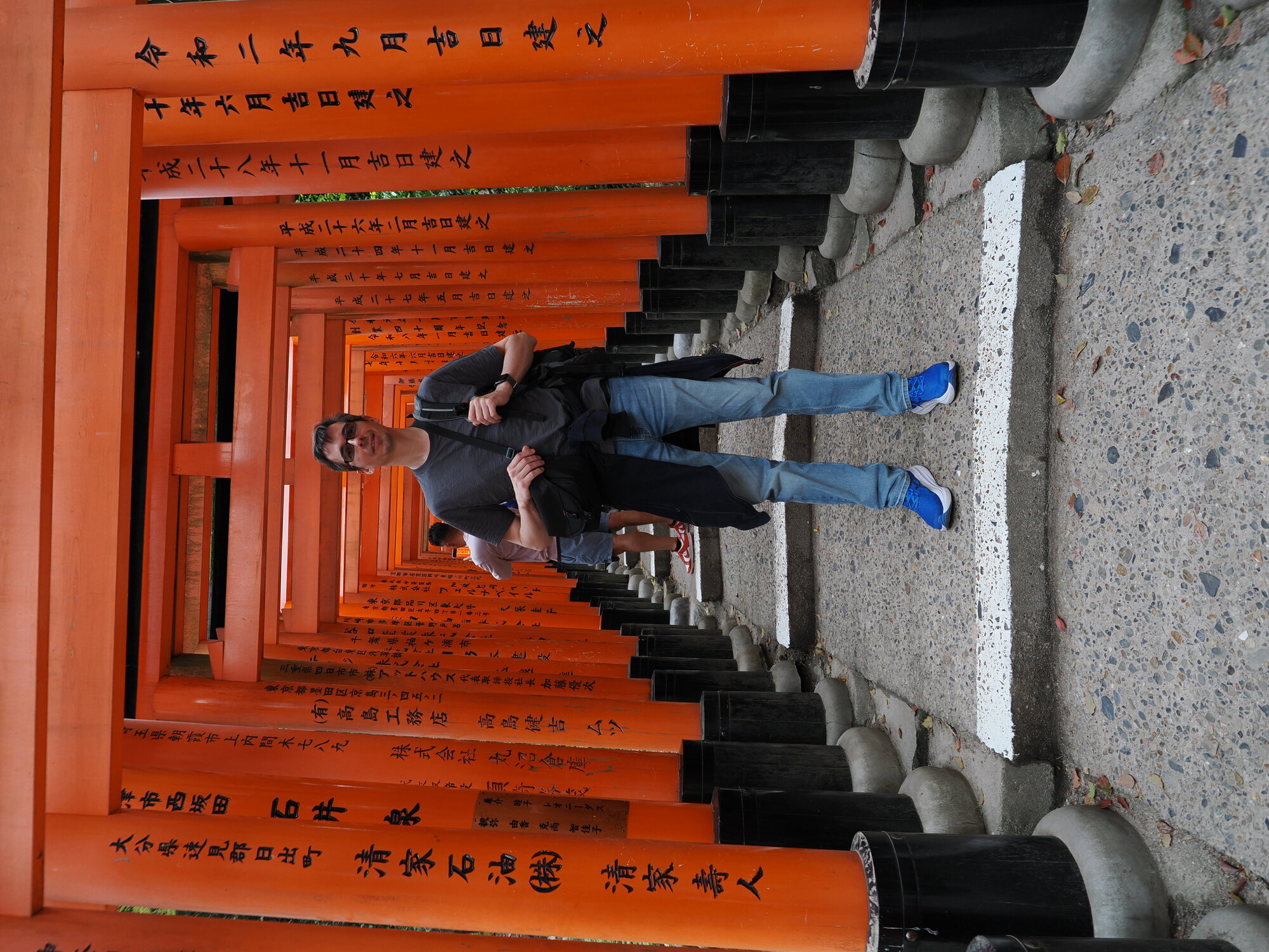 Kamil pozuje wewnątrz tunelu torii Fushimi Inari z inskrypcjami na słupach