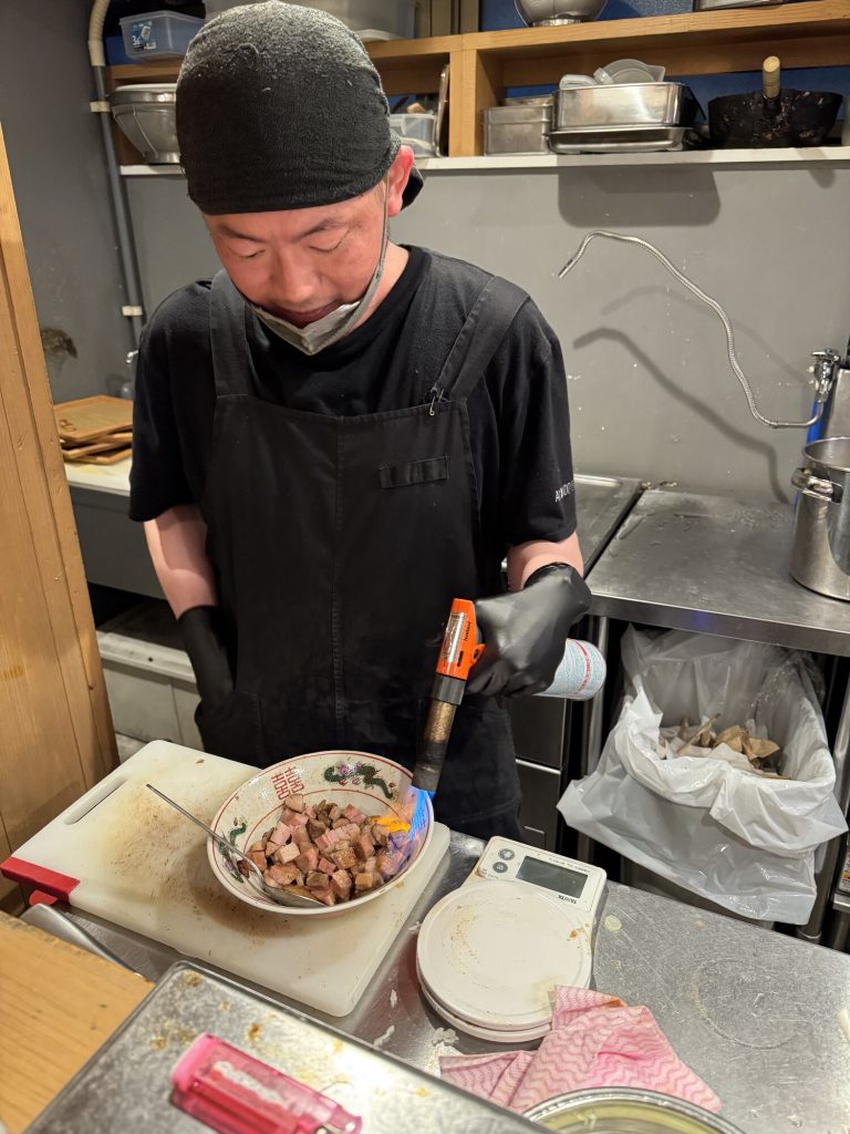 Kucharz opala palnikiem wagyu w ceramicznej miseczce z motywem smoka