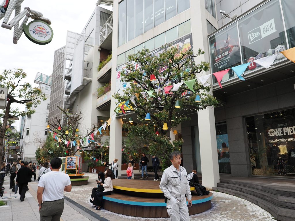 Amerika-mura w Osace — drzewo z proporczykami, sklep Red Bull, szyld New Era i One Piece