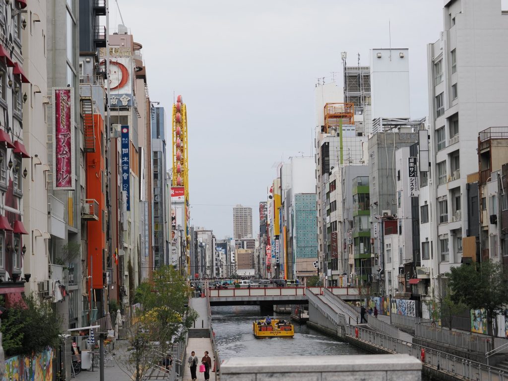 Widok wzdłuż kanału Dōtonbori — żółta łódka Doton, szyldy, kolorowe fasady