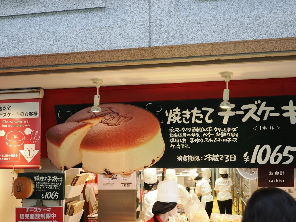 Szyld Rikuro Ojisan z ceną 1065 jenów i piekarzami w tle