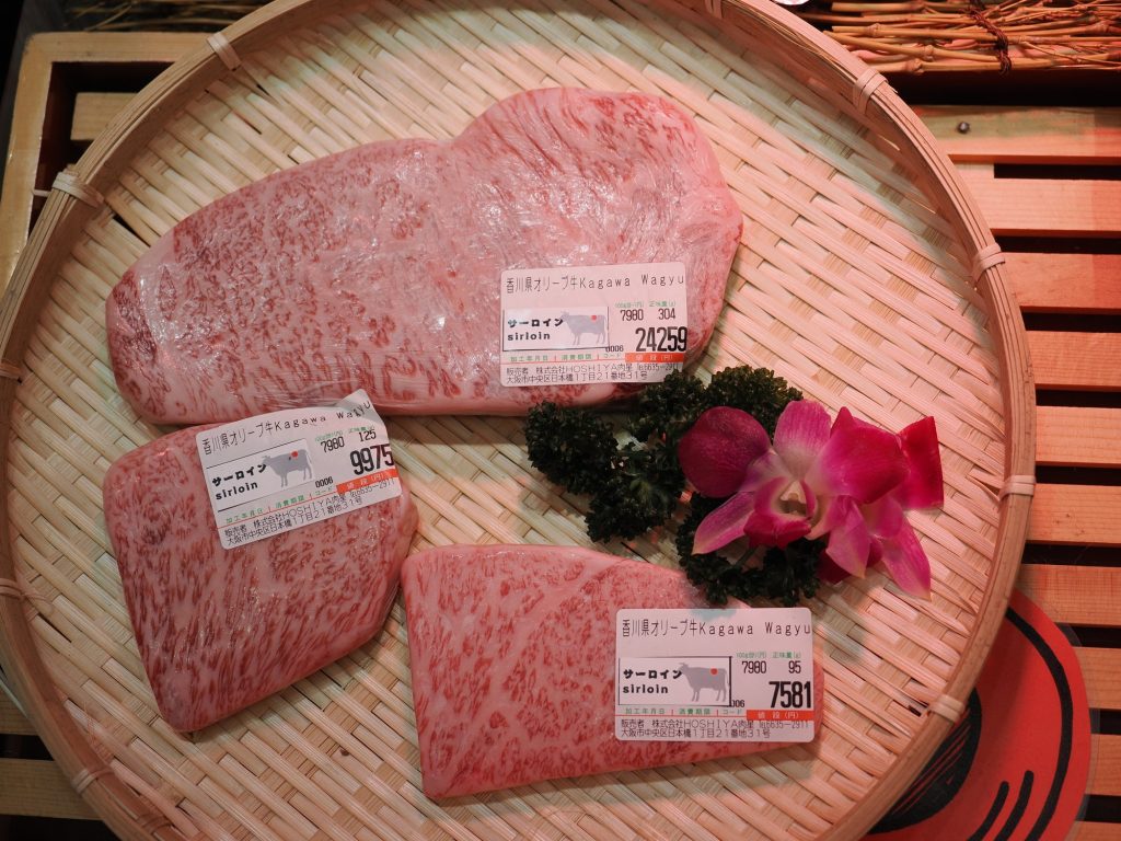 Trzy plastry Kagawa Olive Wagyu sirloin — ceny 7581, 9975 i 24259 jenów
