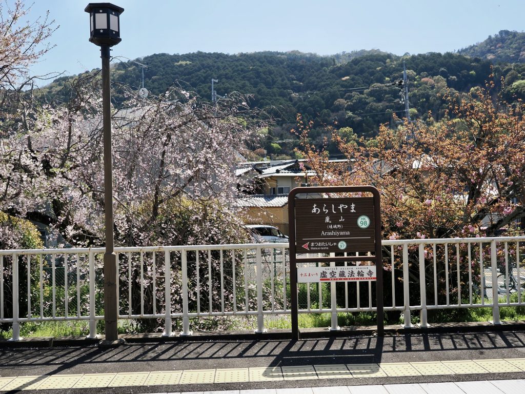 Szyld stacji Arashiyama z wiśniami i górą w tle